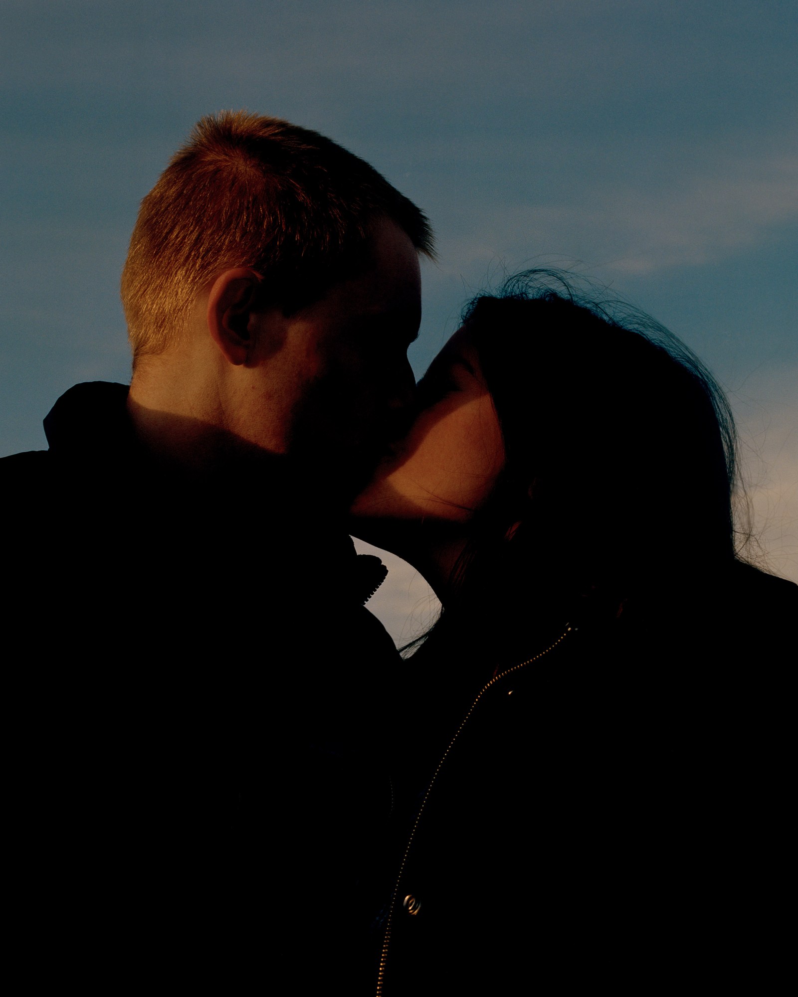 Photograph by Caroline Tompkins of a couple kissing wearing all black in the evening.