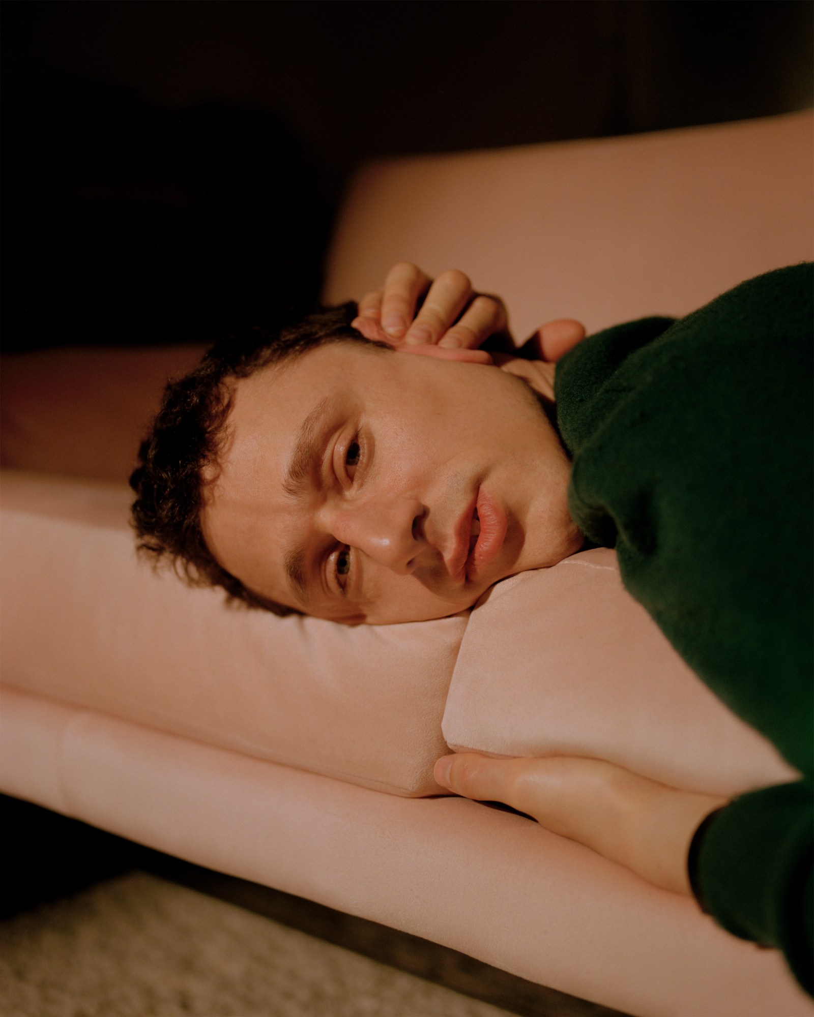 Photograph by Caroline Tompkins of of a man cradling the seat cushion lying down on a sofa.