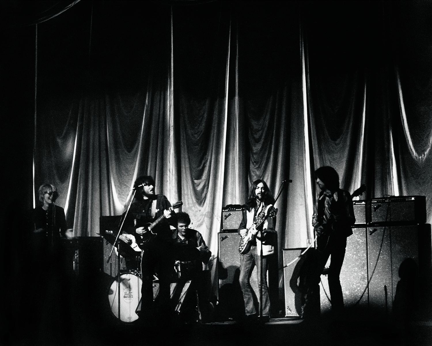 black-and-white image of the beatles performing on stage seen in spotlight