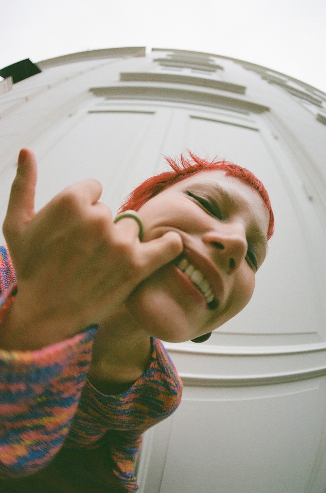 a close up fish-eye shot of a red-haired model with a toothy smile