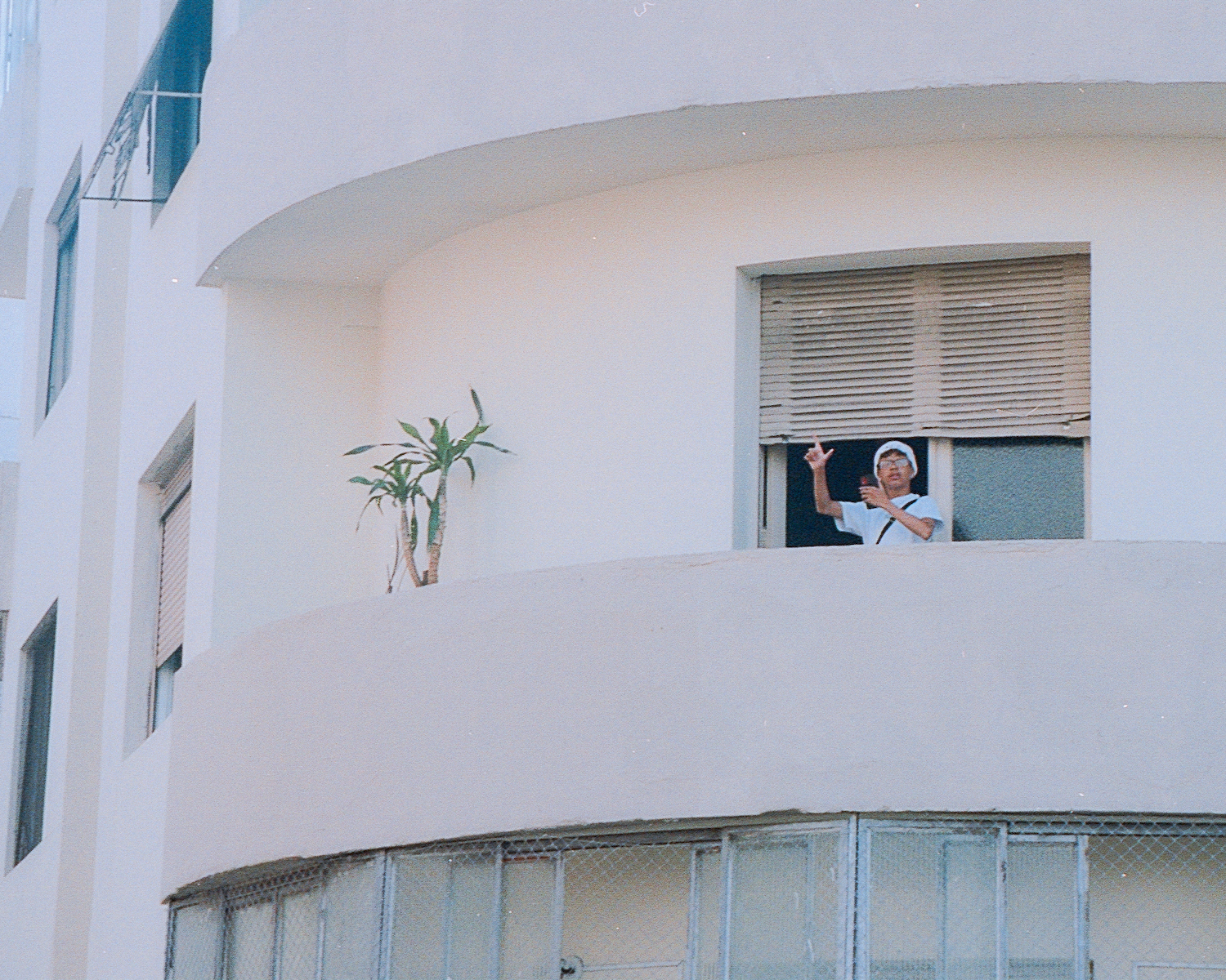 A person stood by a window making L sings with their hands.