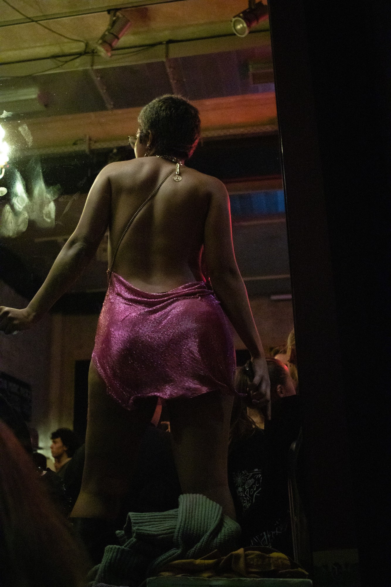 a woman in a pink sequined dress shot from below and behind as she dances