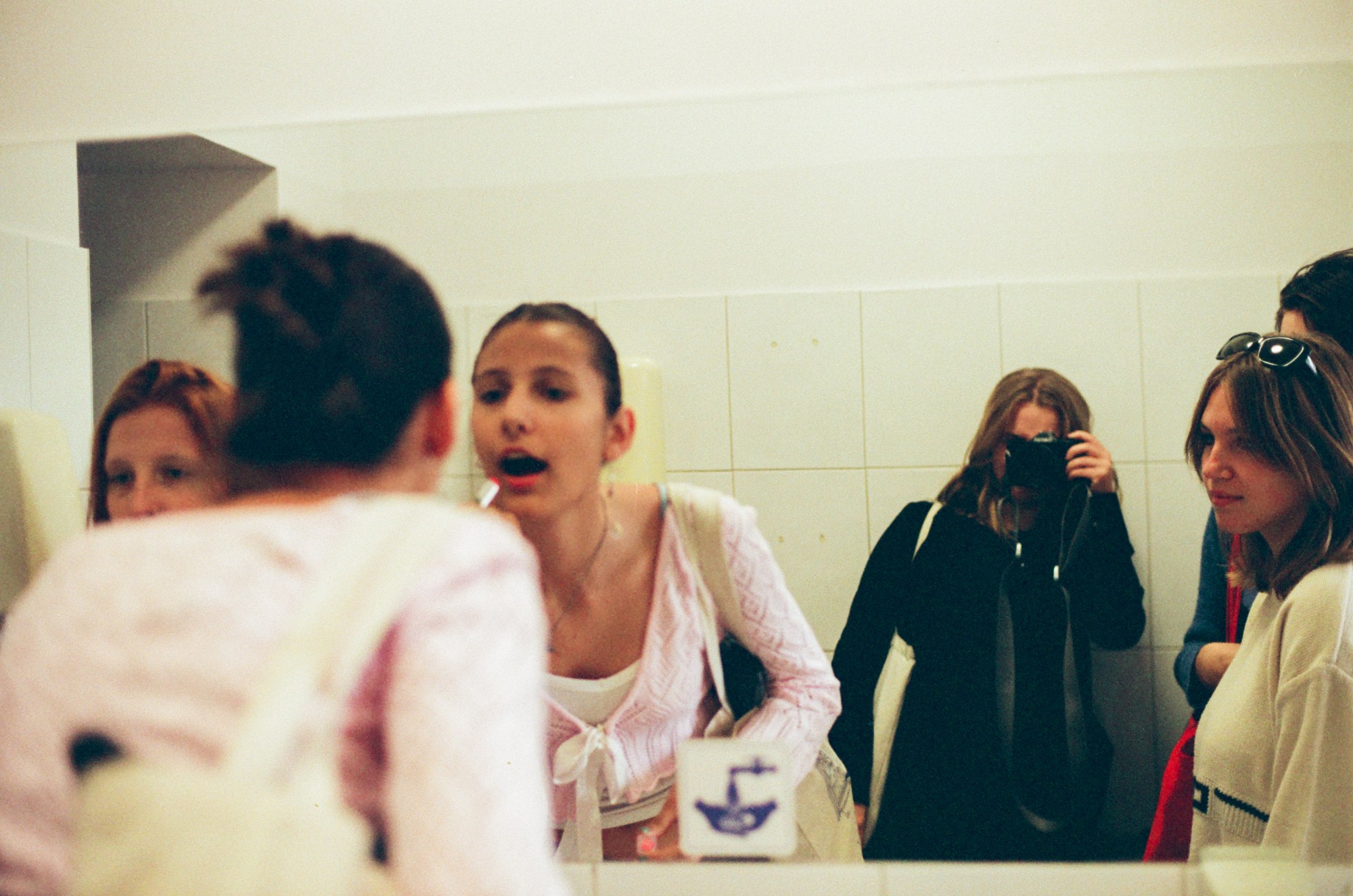 girls doing their make up in front of a bathroom mirror