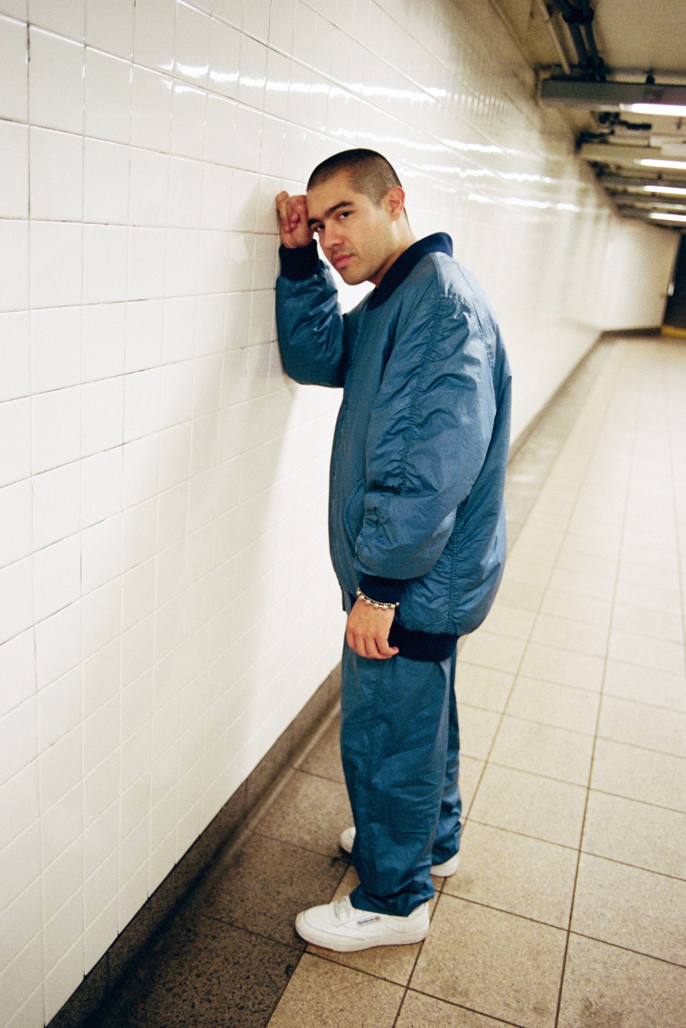 blaketheman1000 standing in the subway station with his fist against the tile wall