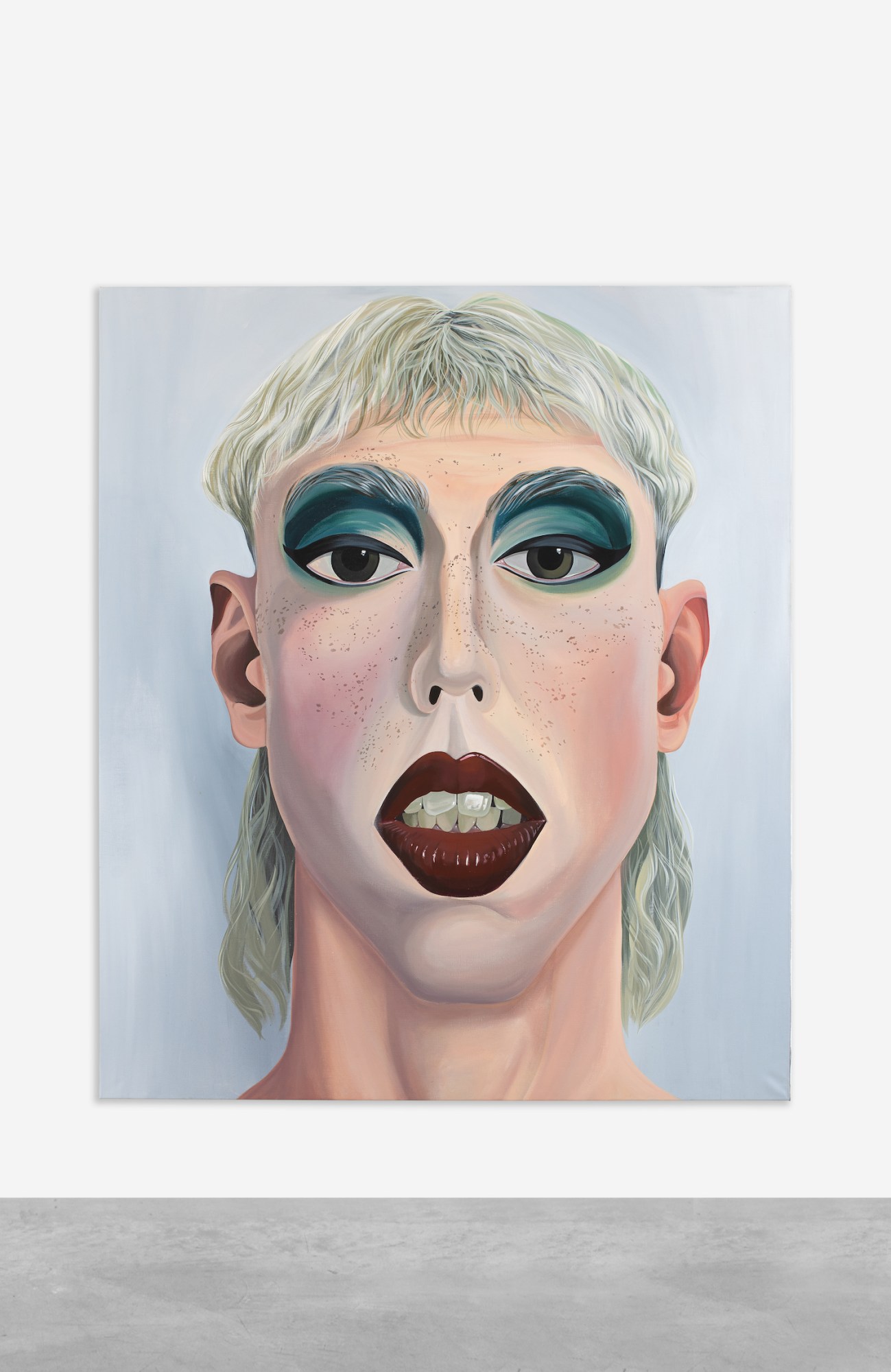 A portrait of a person with blue eye makeup, a blond mullet and brown lipstick