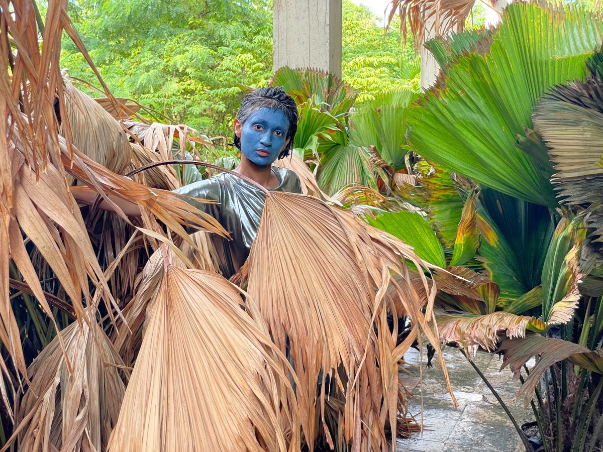 a woman in the forest with blue painted face and silver t-shirt