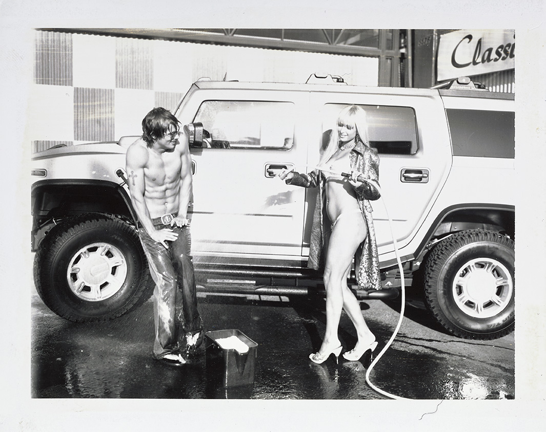 a bikini-clad paris hilton hoses down a topless male model in front of a 4x4