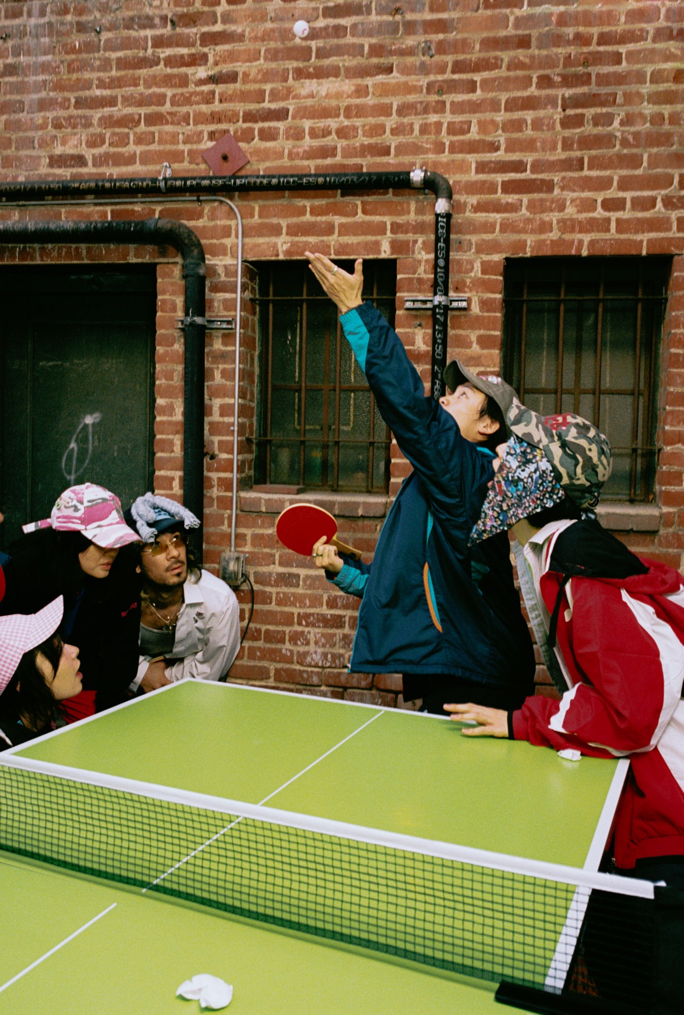 a guy serving a ping-pong ball with his paddle in the air