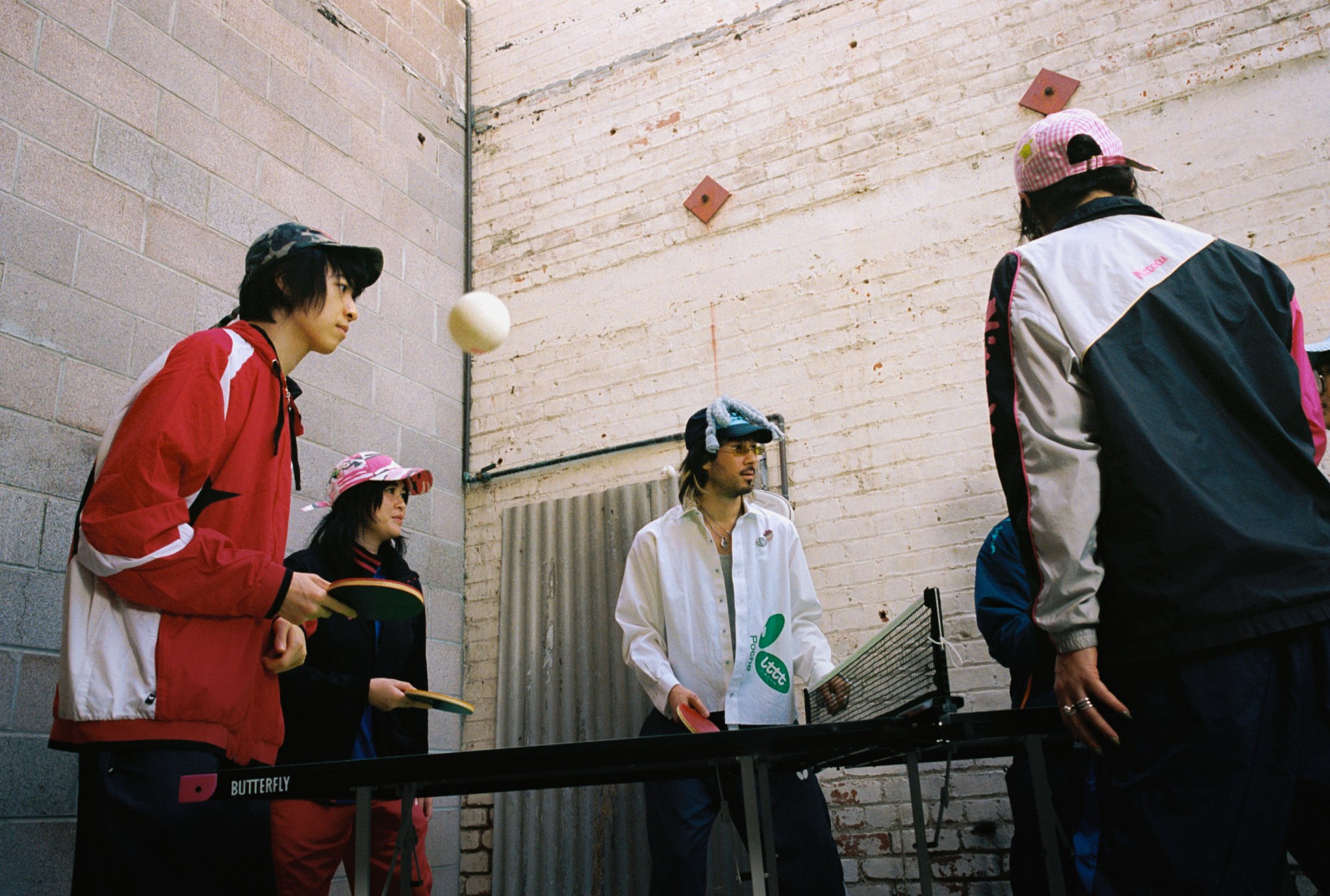 a group of people wearing poche studio and playing ping-pong