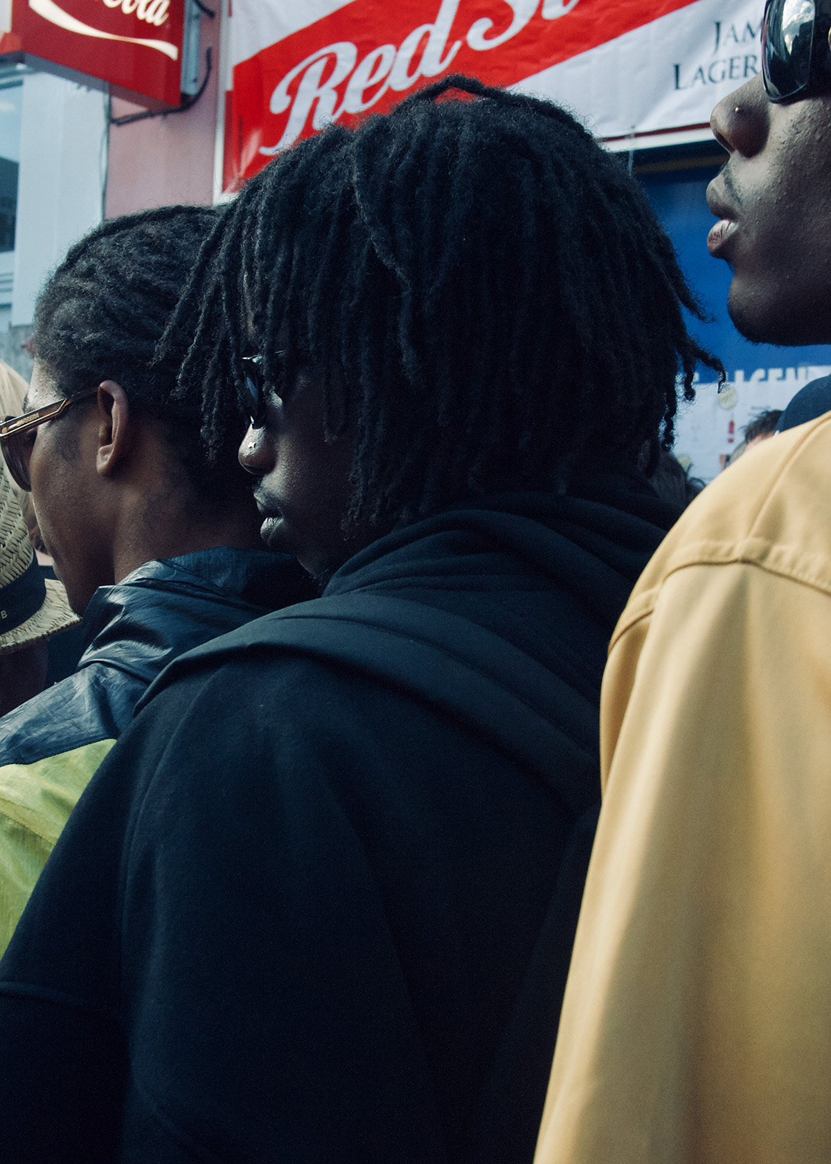 Three men lined up wearing coats and sunglasses.