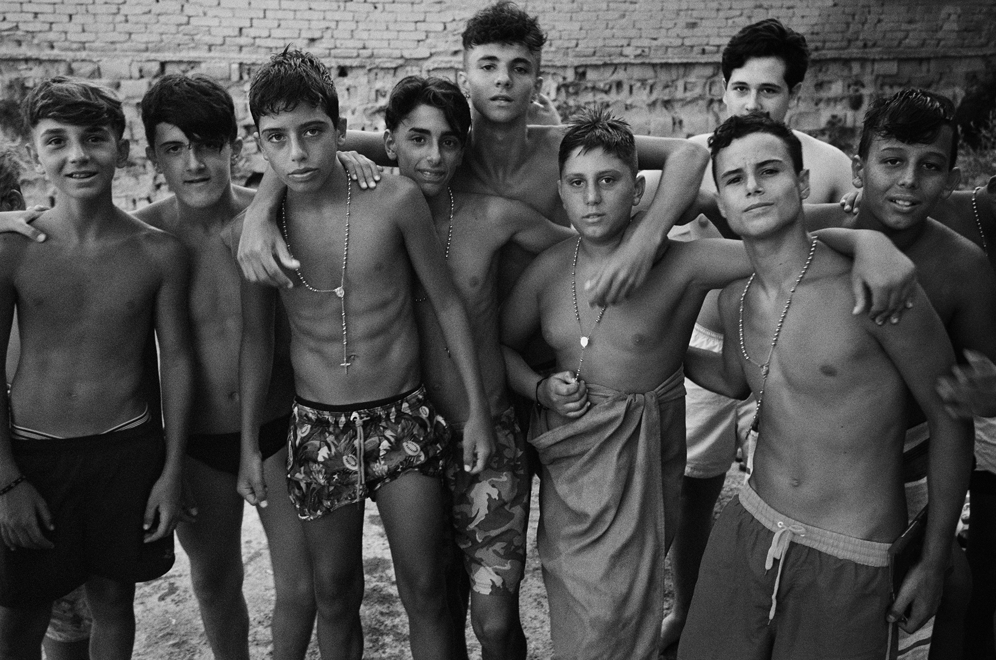 a group of teen boys in swimwear pose with their arms around each other