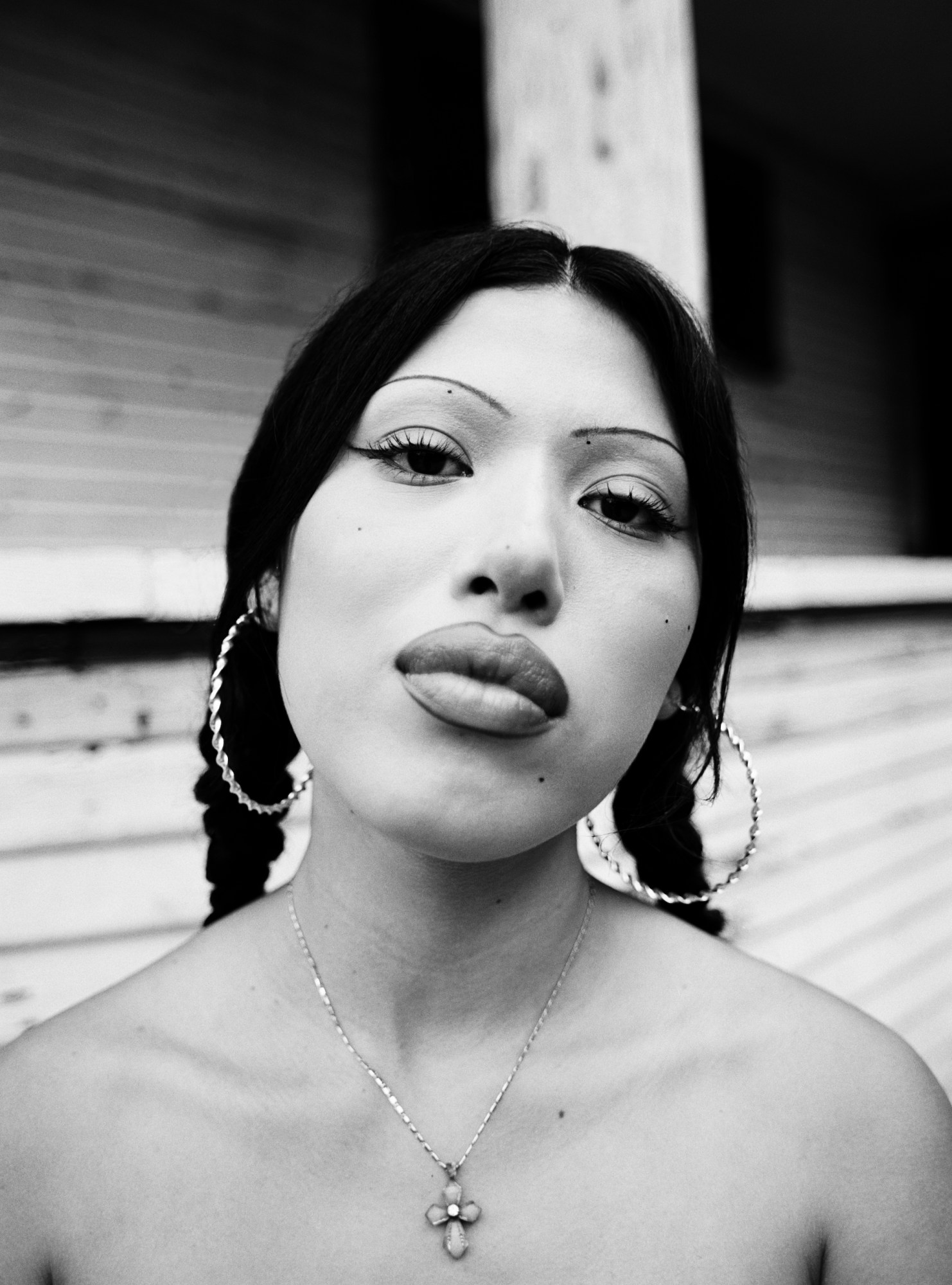 a close up of a girl with painted eyebrows, hoop earrings and silver jewelry