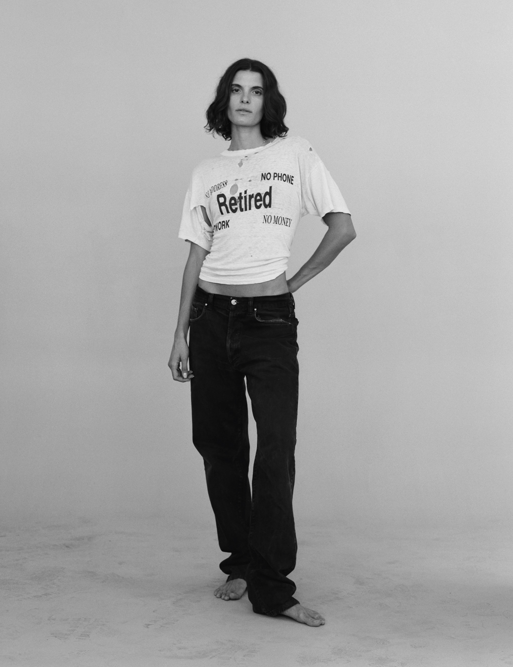 a model wears a vintage T-shirt that reads RETIRED with a pair of jeans