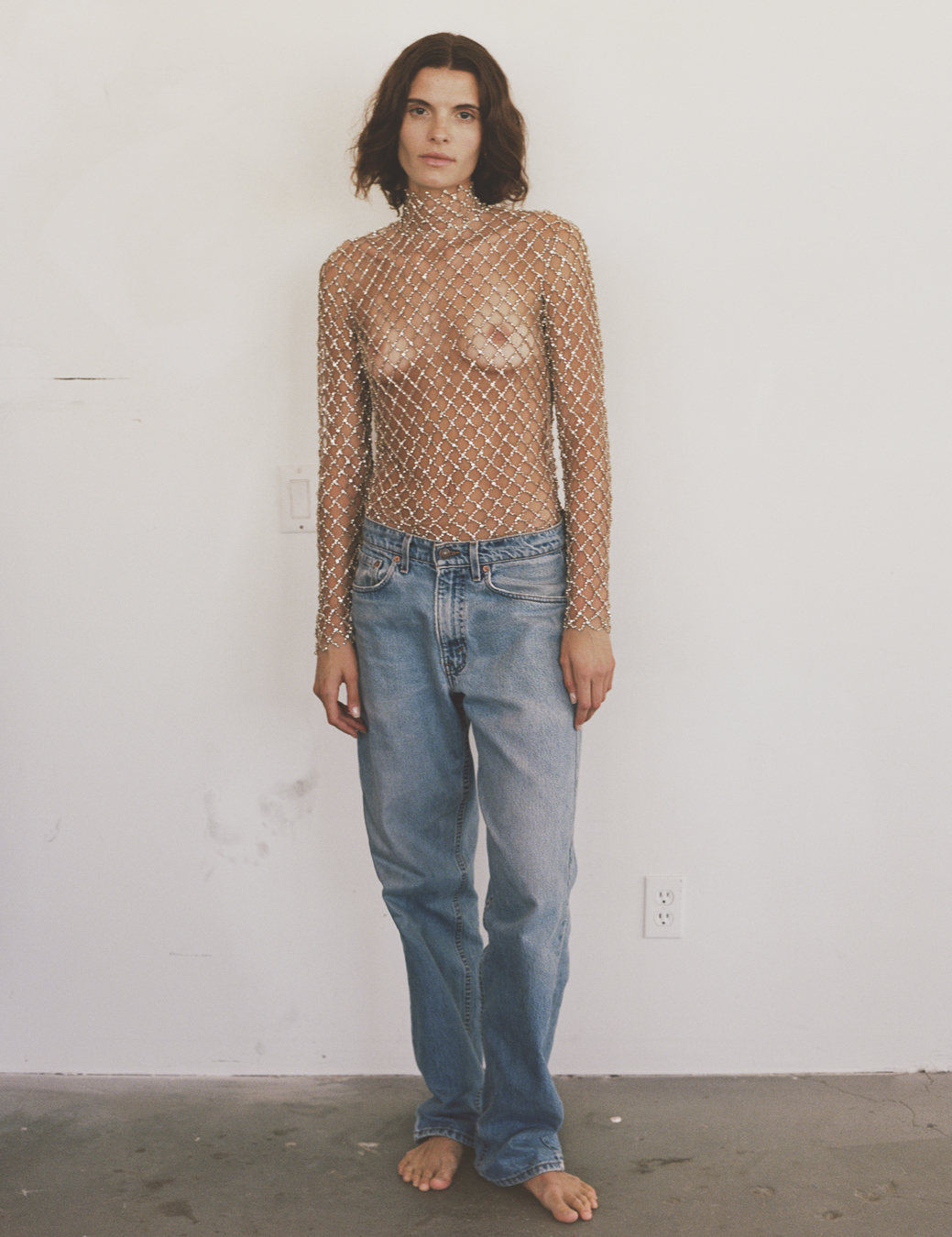 a model wears a bejewelled sheer net-type top with stonewash boyfriend jeans