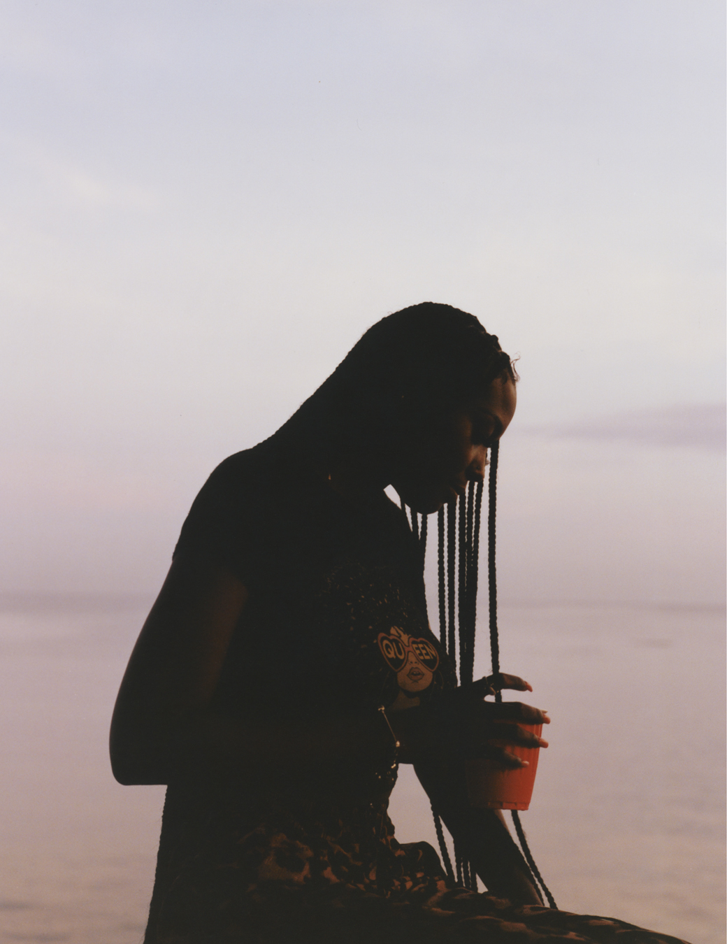 Mezzy holding a cup in front of the ocean photographed by Jeano Edwards for i-D’s The Royalty Issue, no. 370, Winter 2022