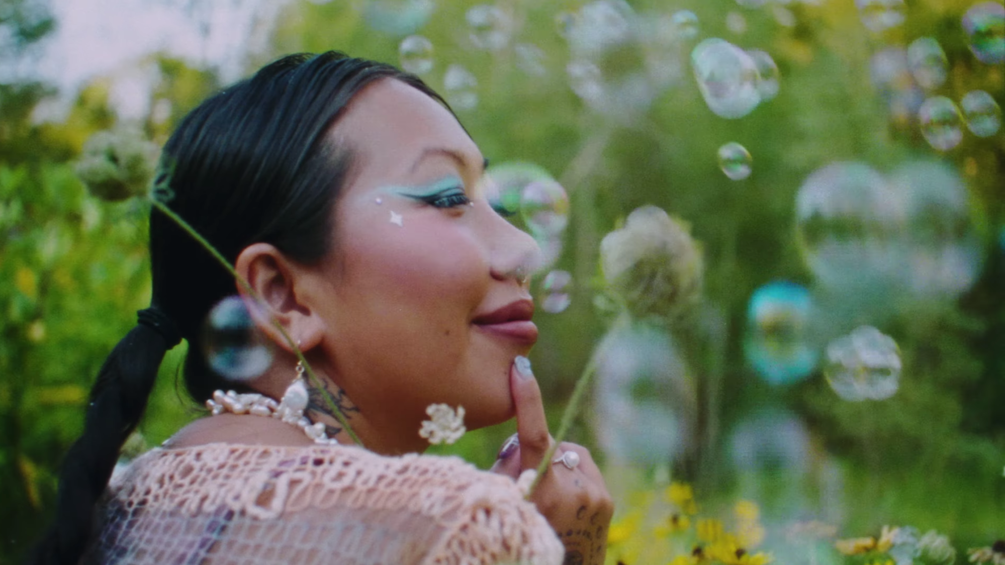 Mimi Zhu sitting in a field, surrounded by bubbles