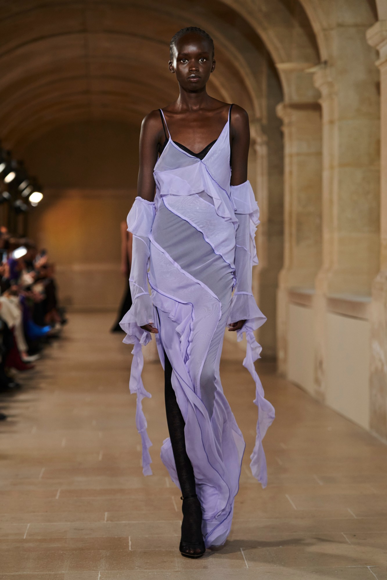 A model walking the runway at Paris Fashion Week wearing a purple gown