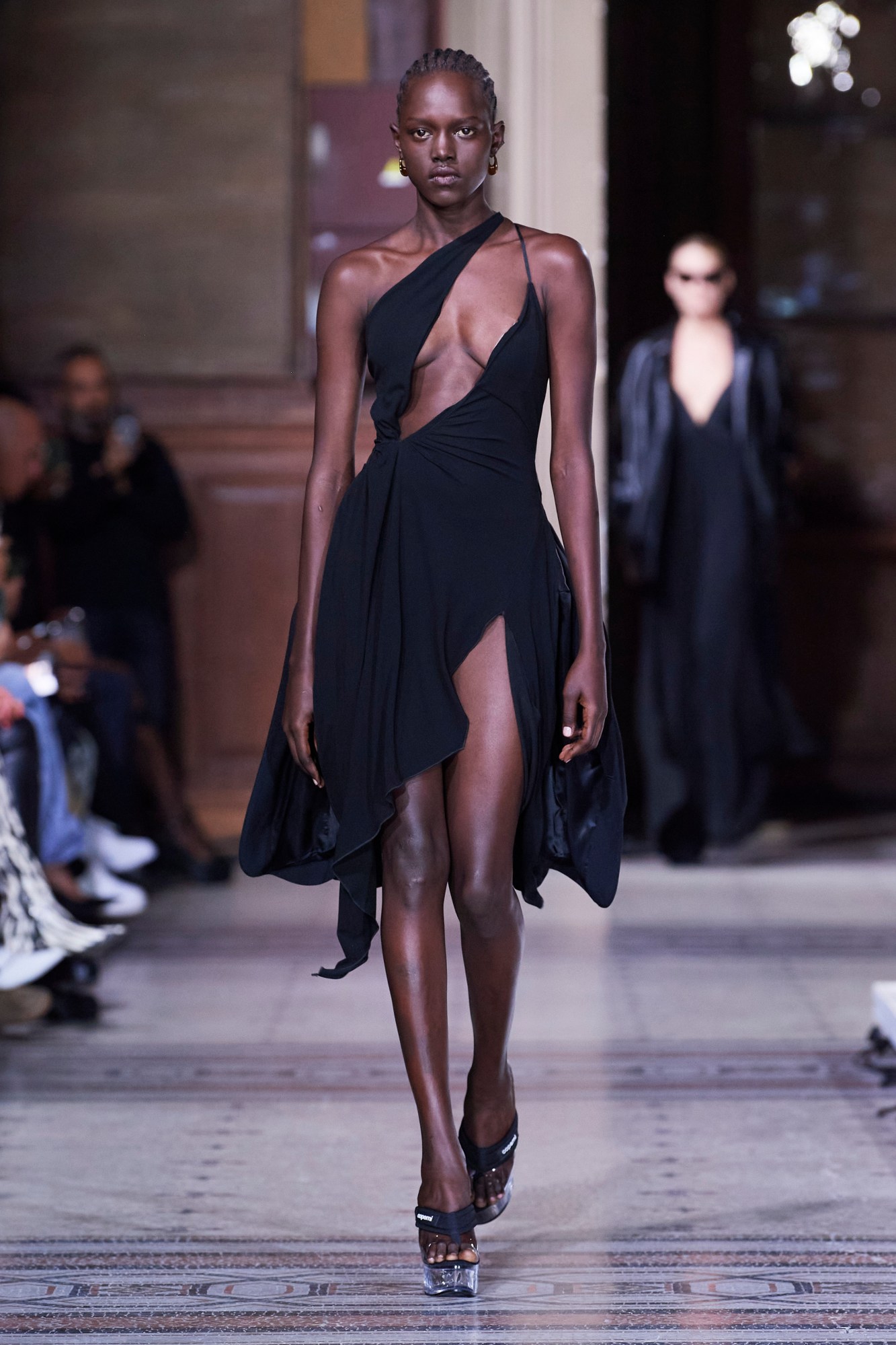 A model walking the runway at Paris Fashion Week wearing a black dress