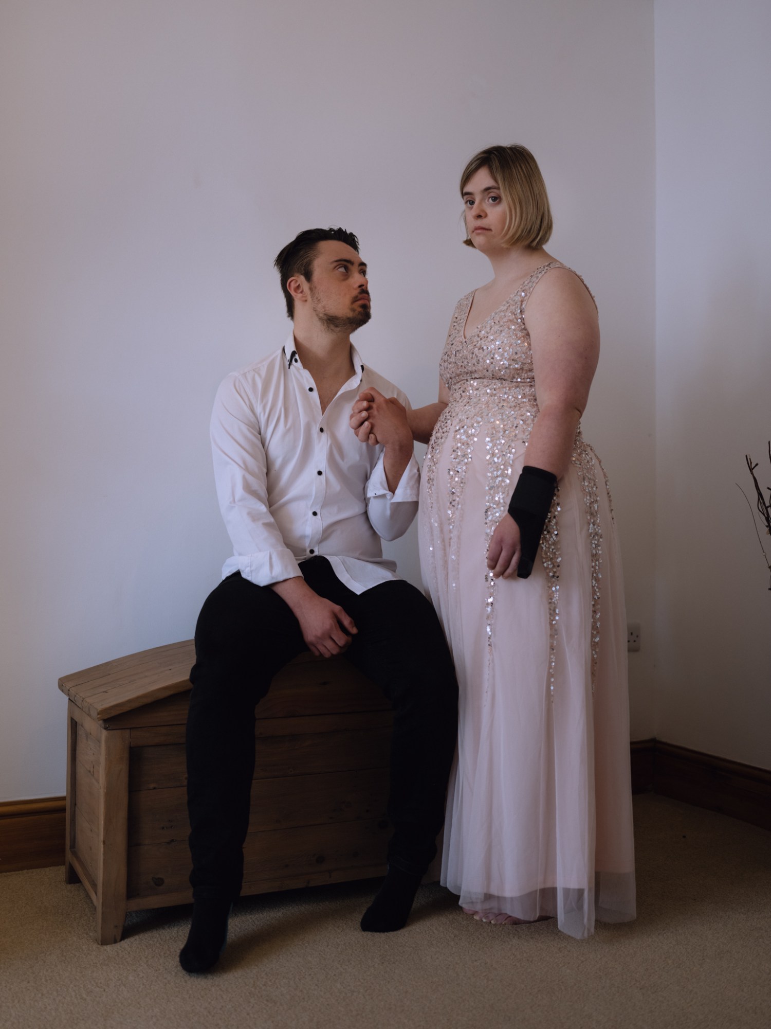 a couple in formalwear hold hands in a minimalistic room