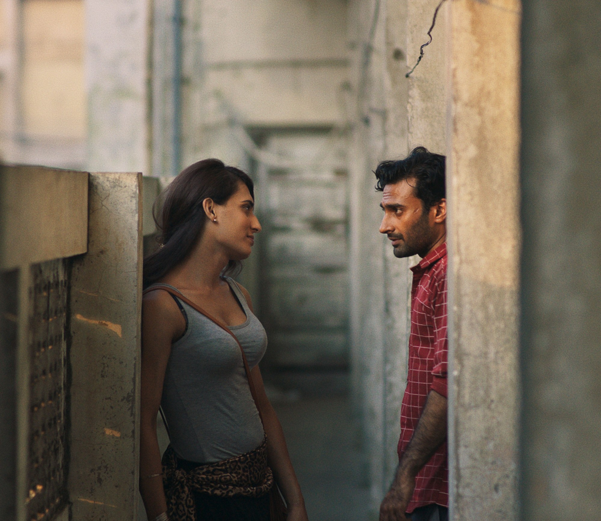 a couple looks at each other in a sunlit alleyway