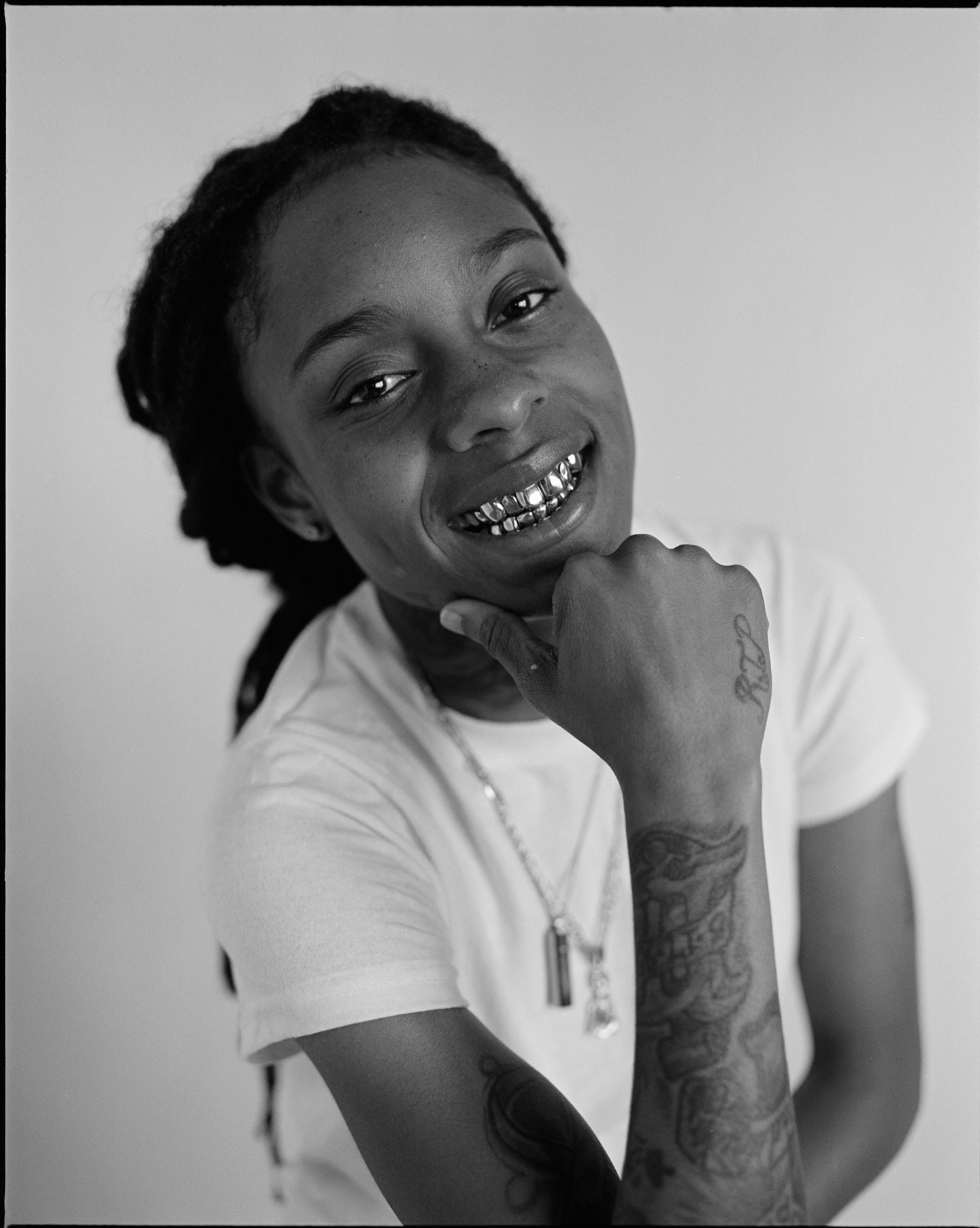 black-and-white headshot of pig the gemini in a white t shirt smiling at the camera