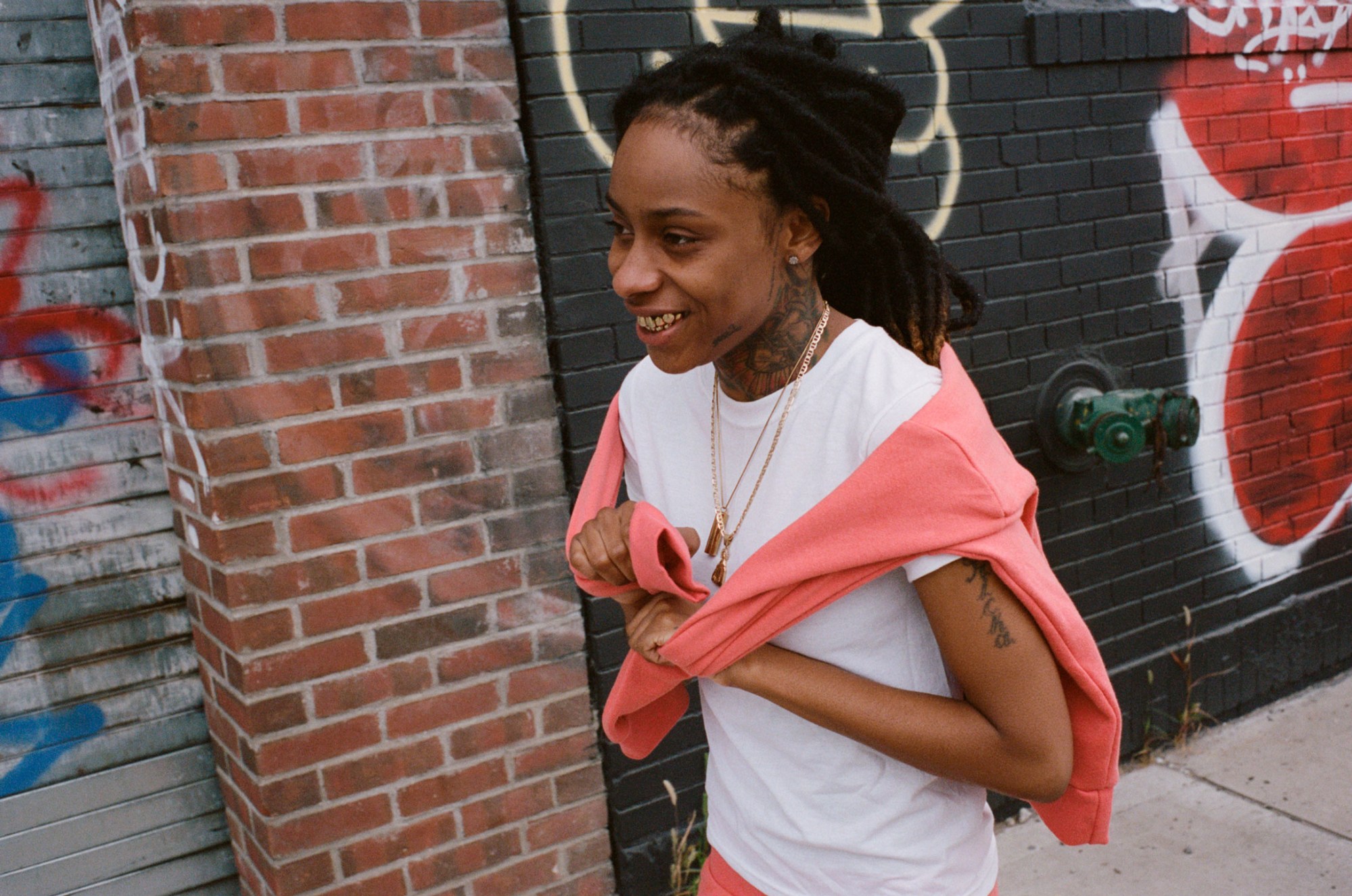 pig the gemini shot in profile on a street in miami, wearing a white t-shirt and pink tracksuit