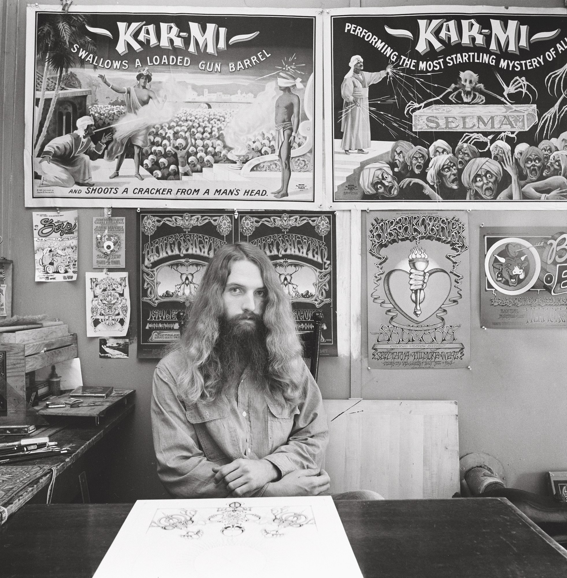 black-and-white image of a 1960s artist in his studio with long hair and beard