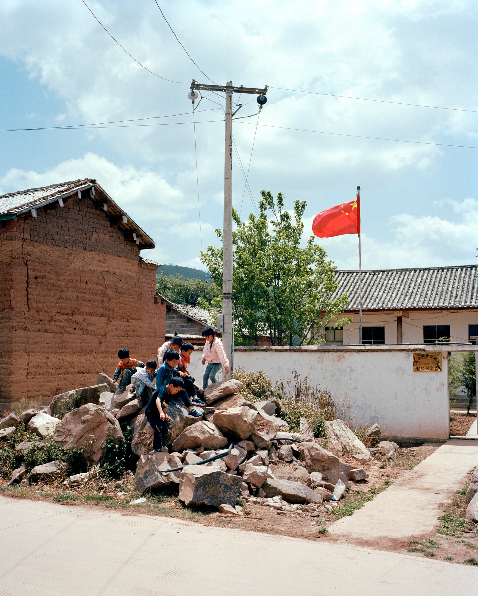 children play on a pile of rubble under a chinese flag