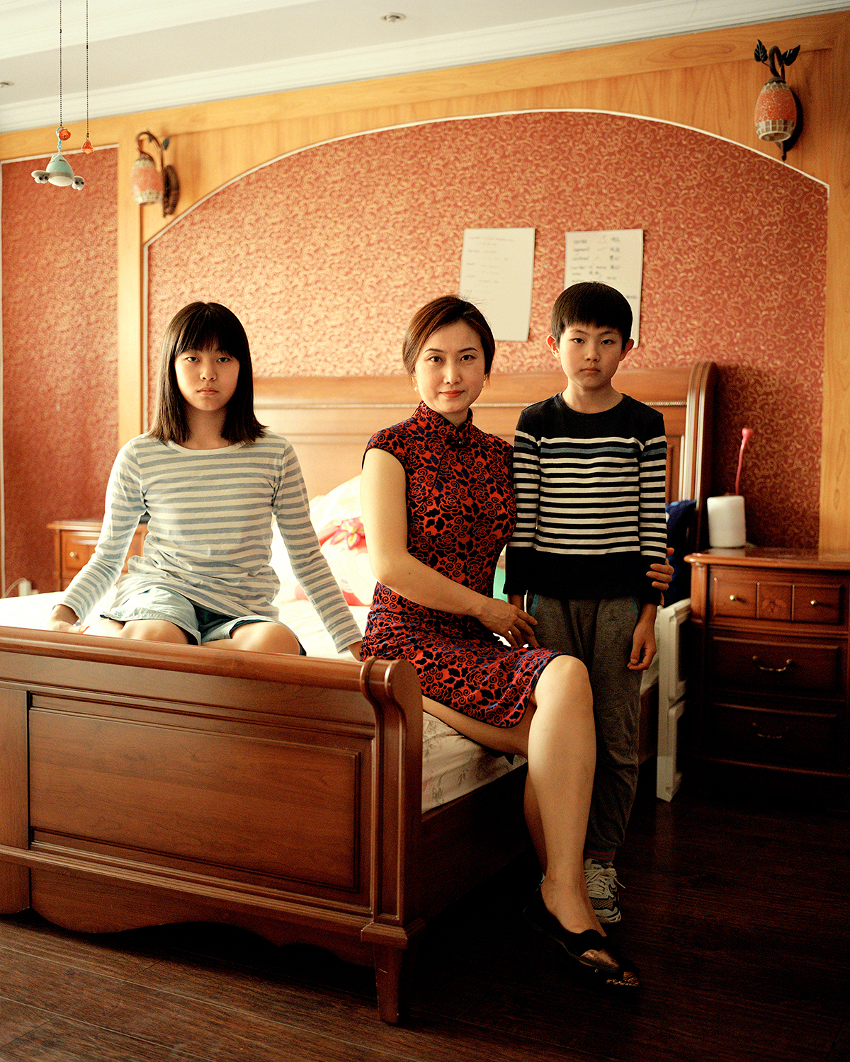 a mother and her two children sit smartly on a wooden bed