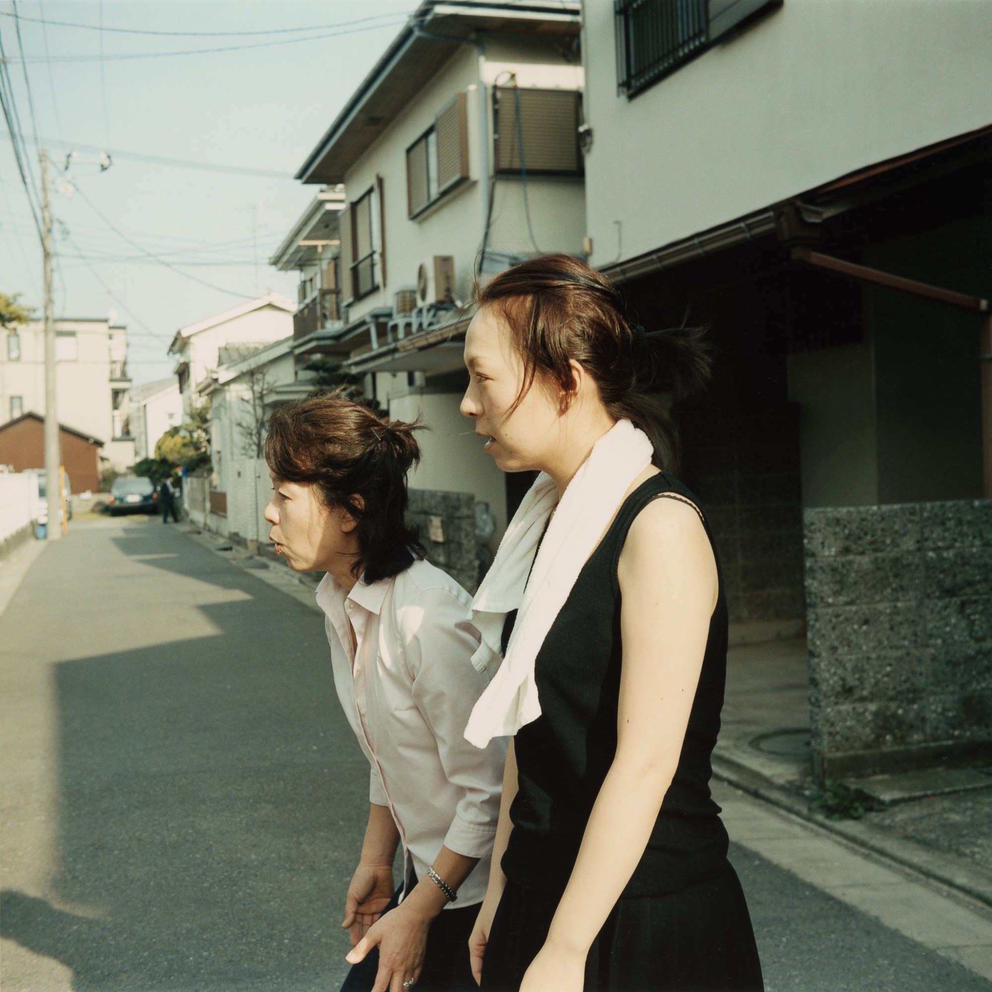 Two women look engrossed at something on a street