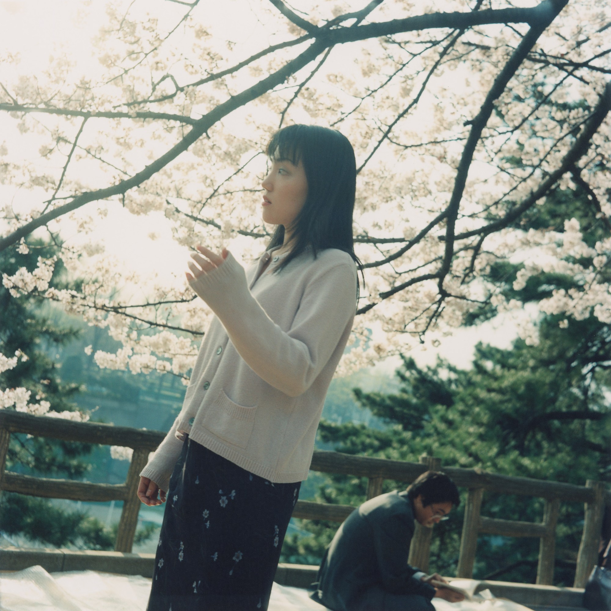 A woman holds onto a branch of blossom