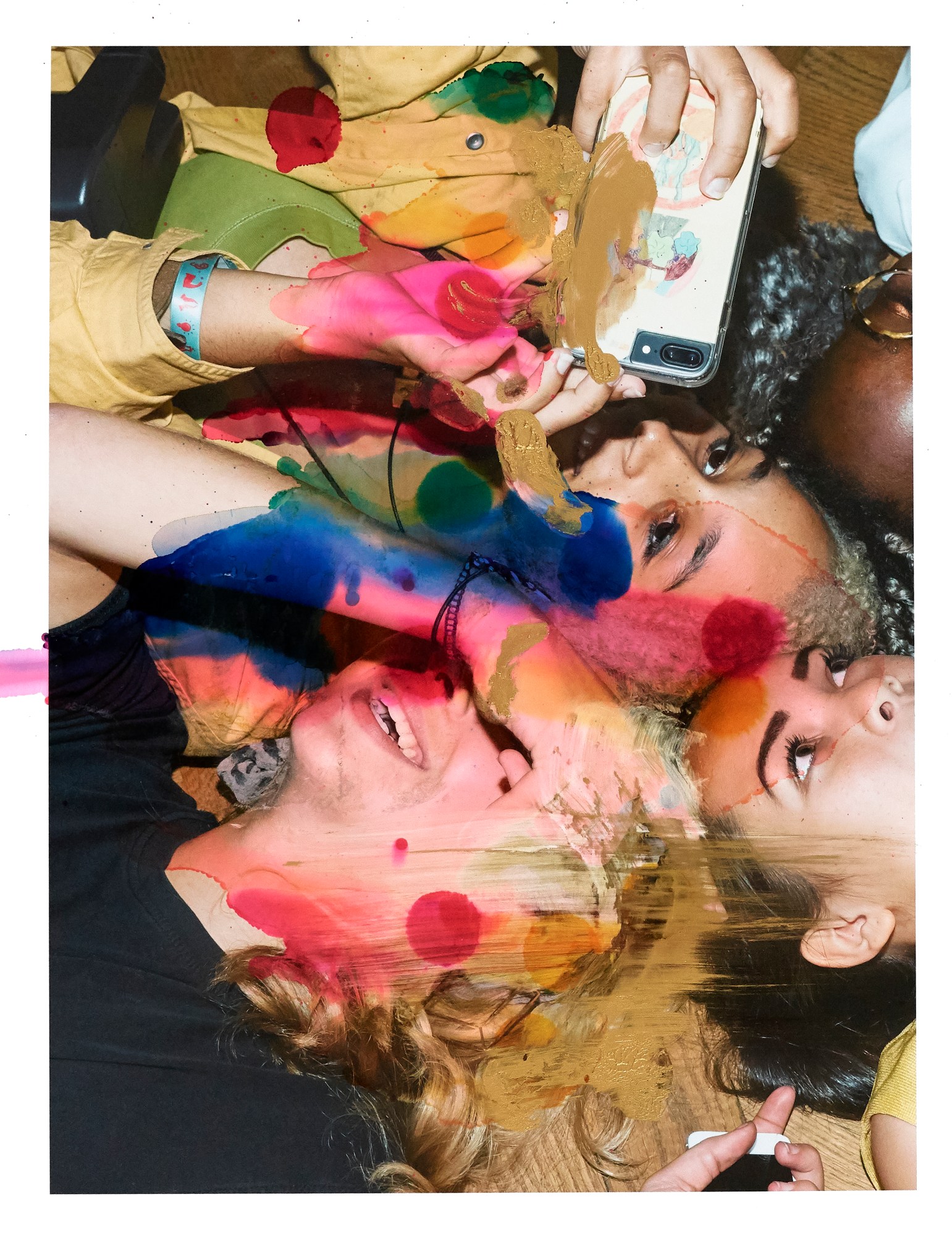 paint splattered image of partygoers lying on a wooden floor taking a picture with an iphone