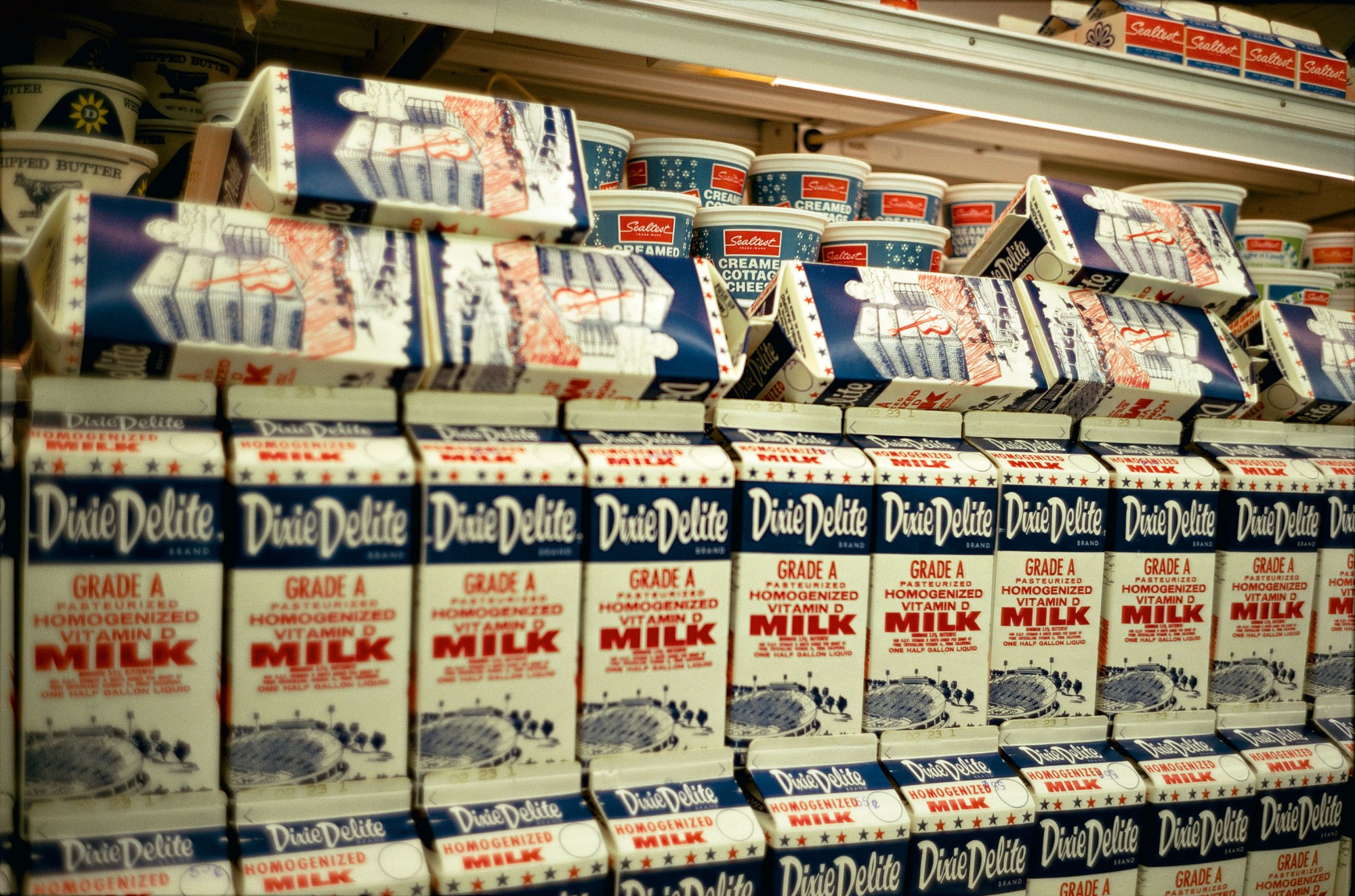 milk cartons on a shop floor shelf, with cottage cheese behind them