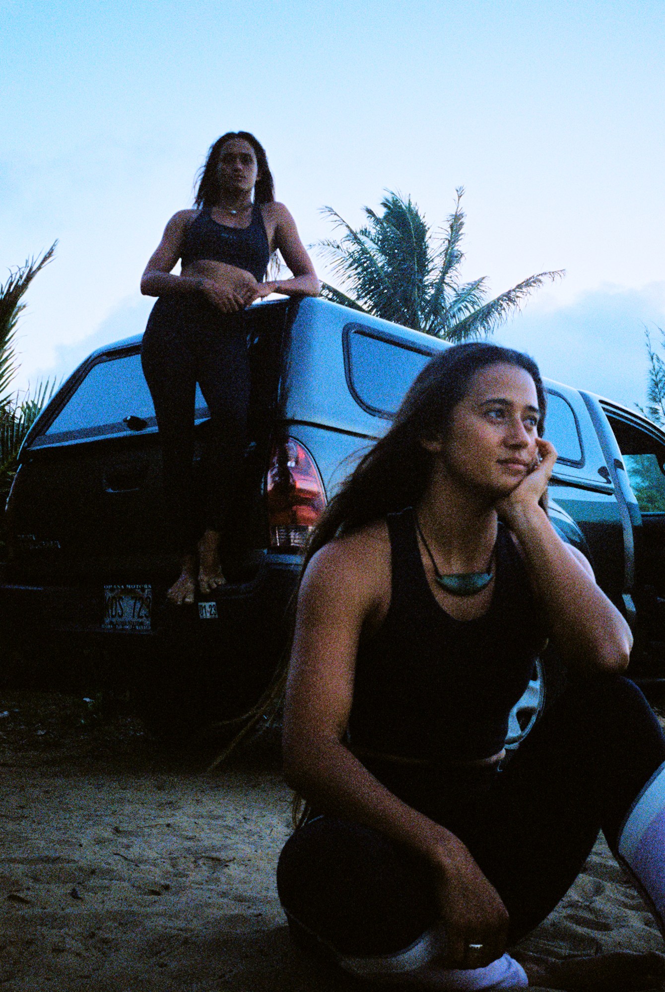 two girls posing in front of a car on the beach in hawaii