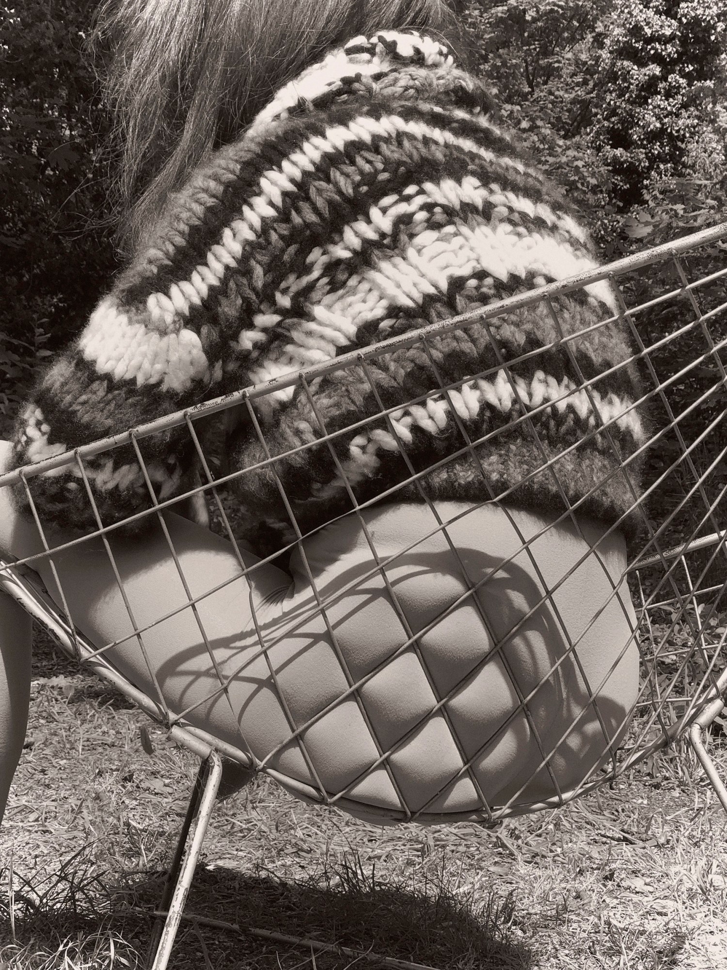 a model sits on a hammock outside, nude from the waist down