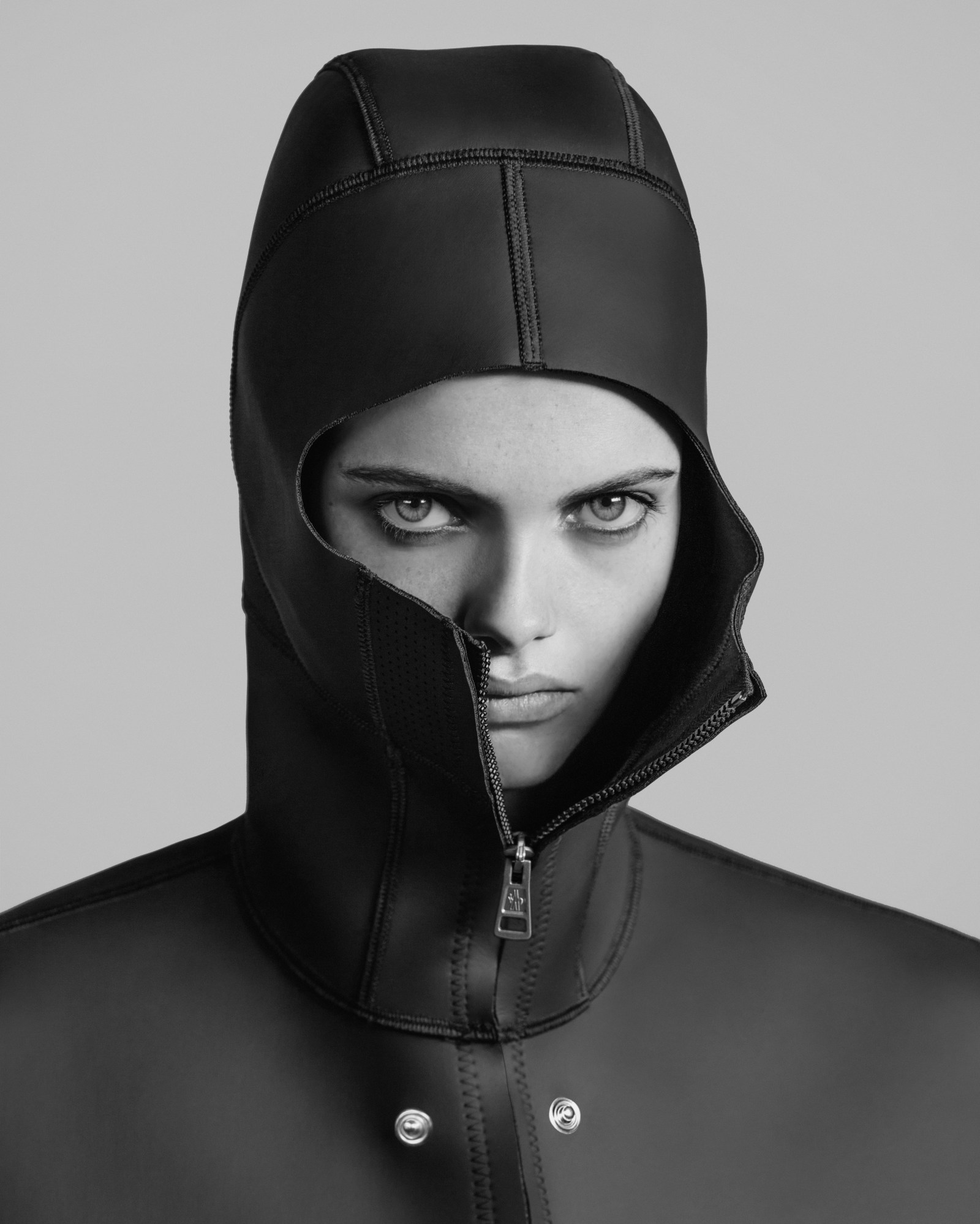 a headshot of a model wearing a neoprene jacket, only her eyes and half a face exposed