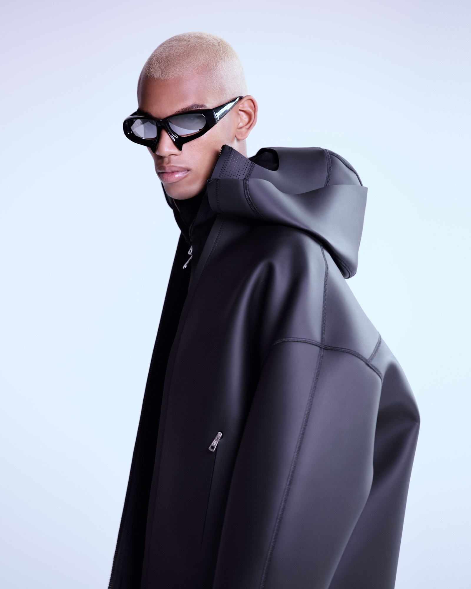 a model wears mirrored sunglasses and a neoprene jacket