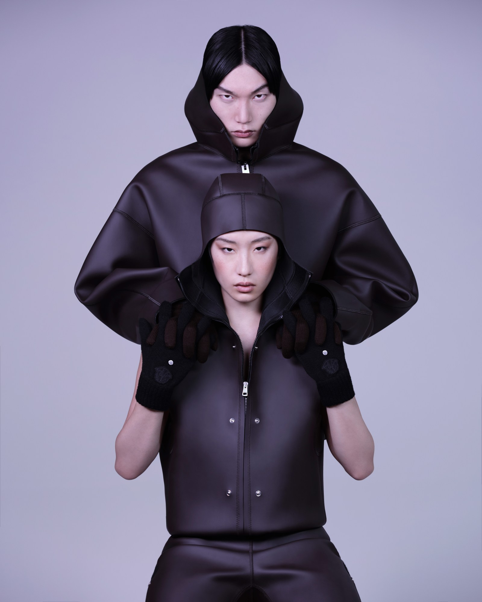 two models wearing black waterproofs pose in front of one another