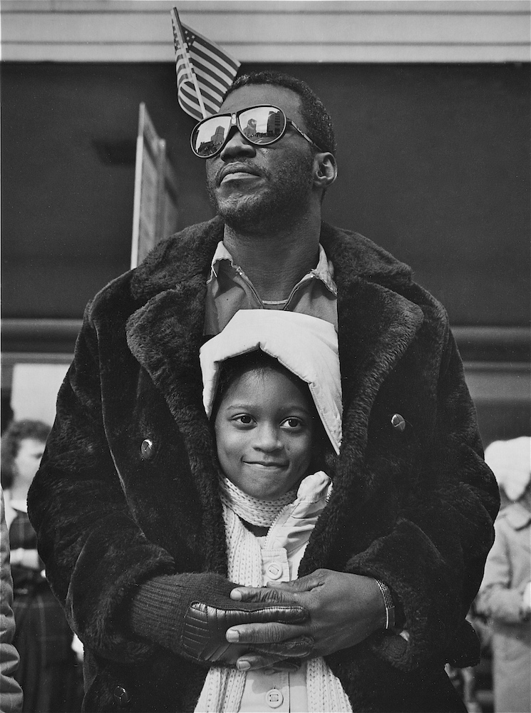 A young girl staying warm inside her fathers fur coat