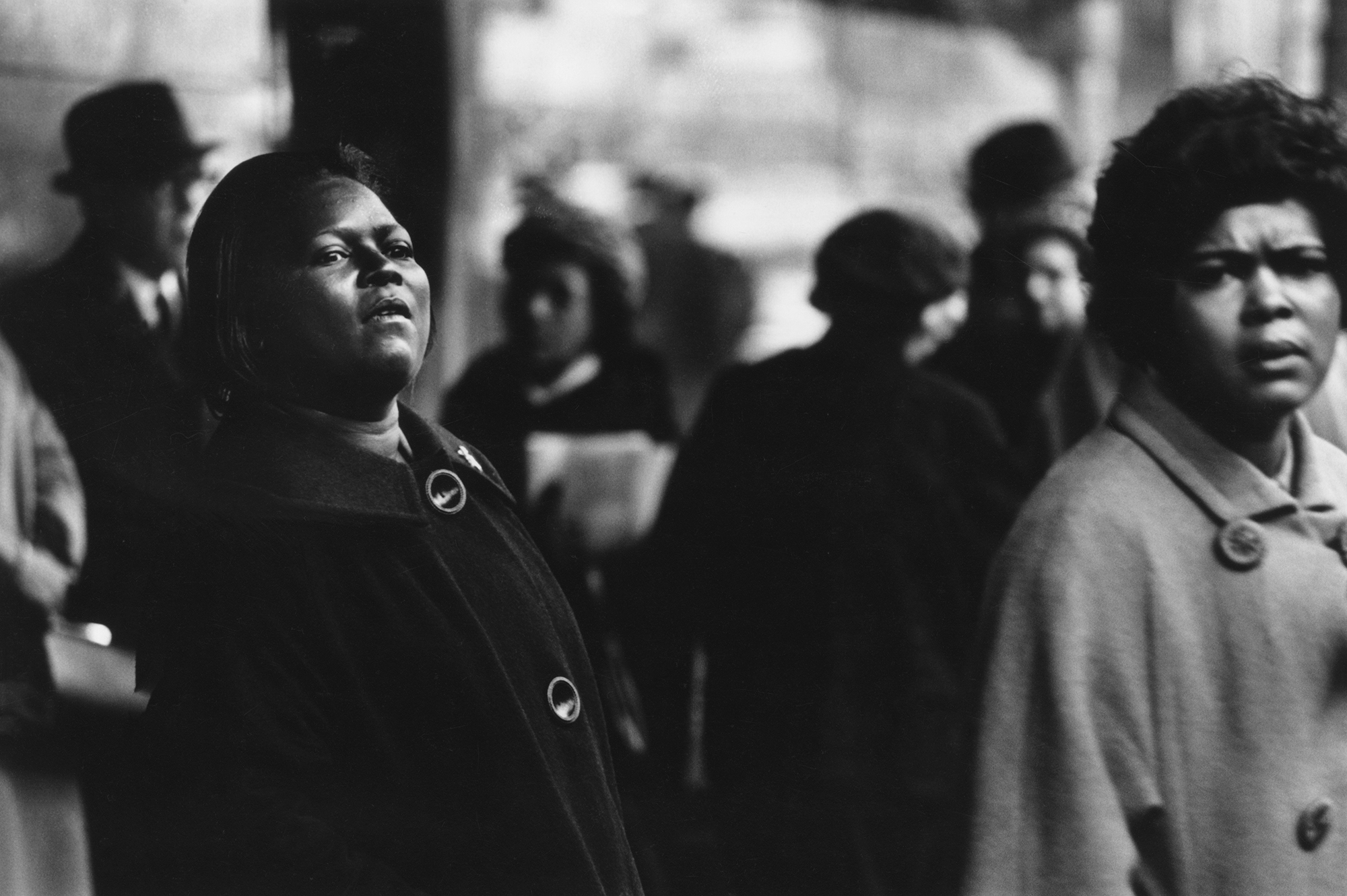 two women in long winter coats looks into the distance