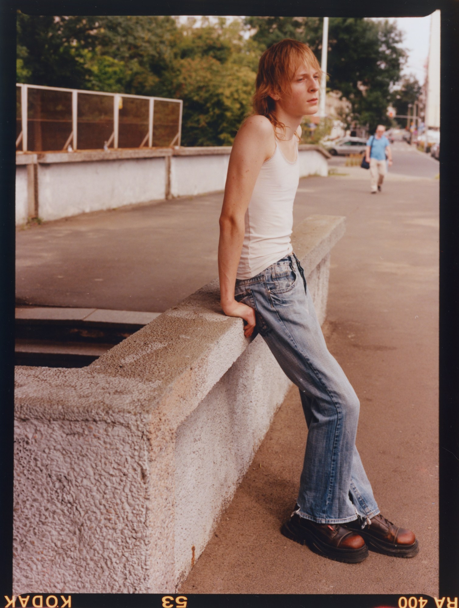 A teenager wearing blue jeans leaning against a concrete bench