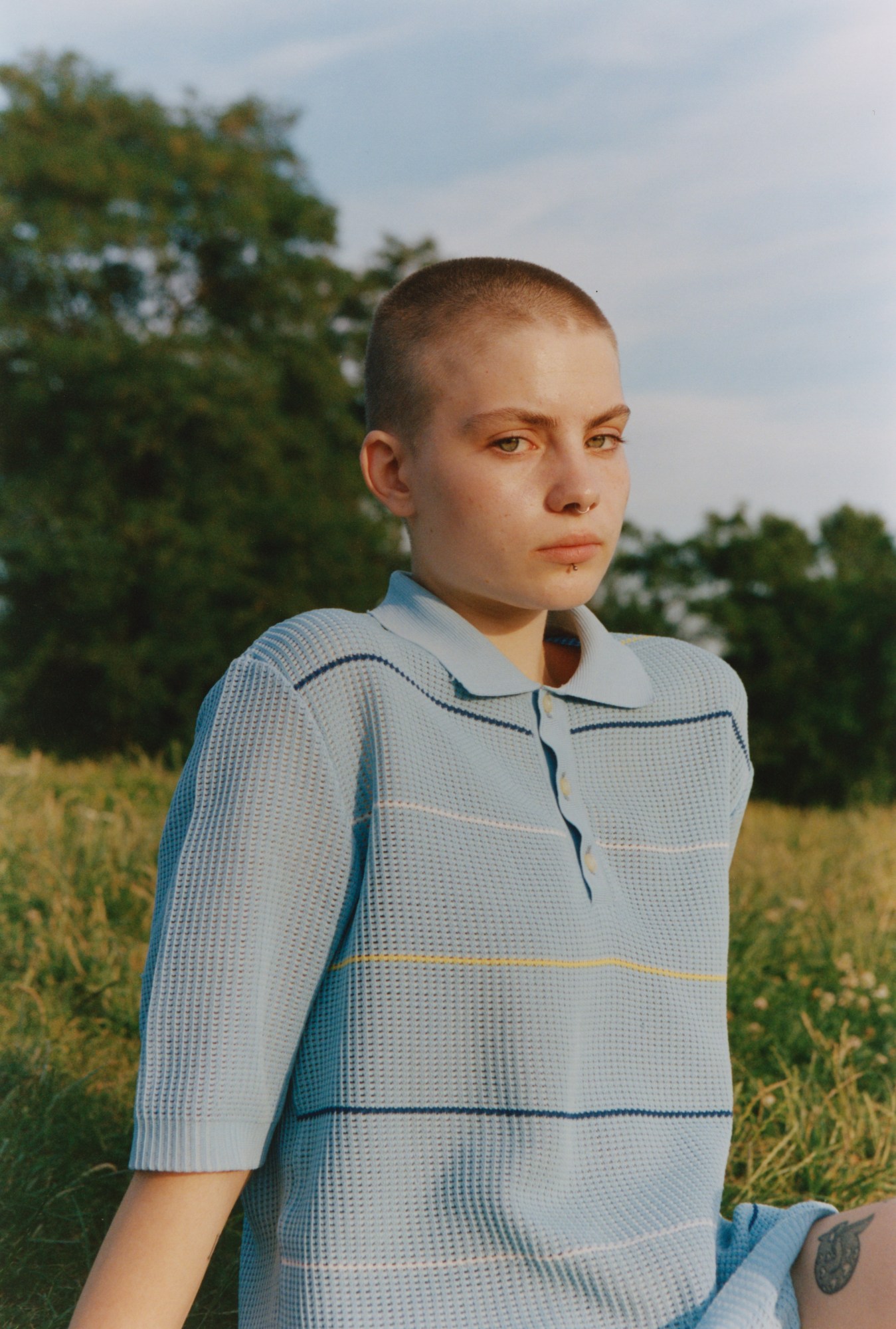 A bald teenager in a blue t-shirt pouting