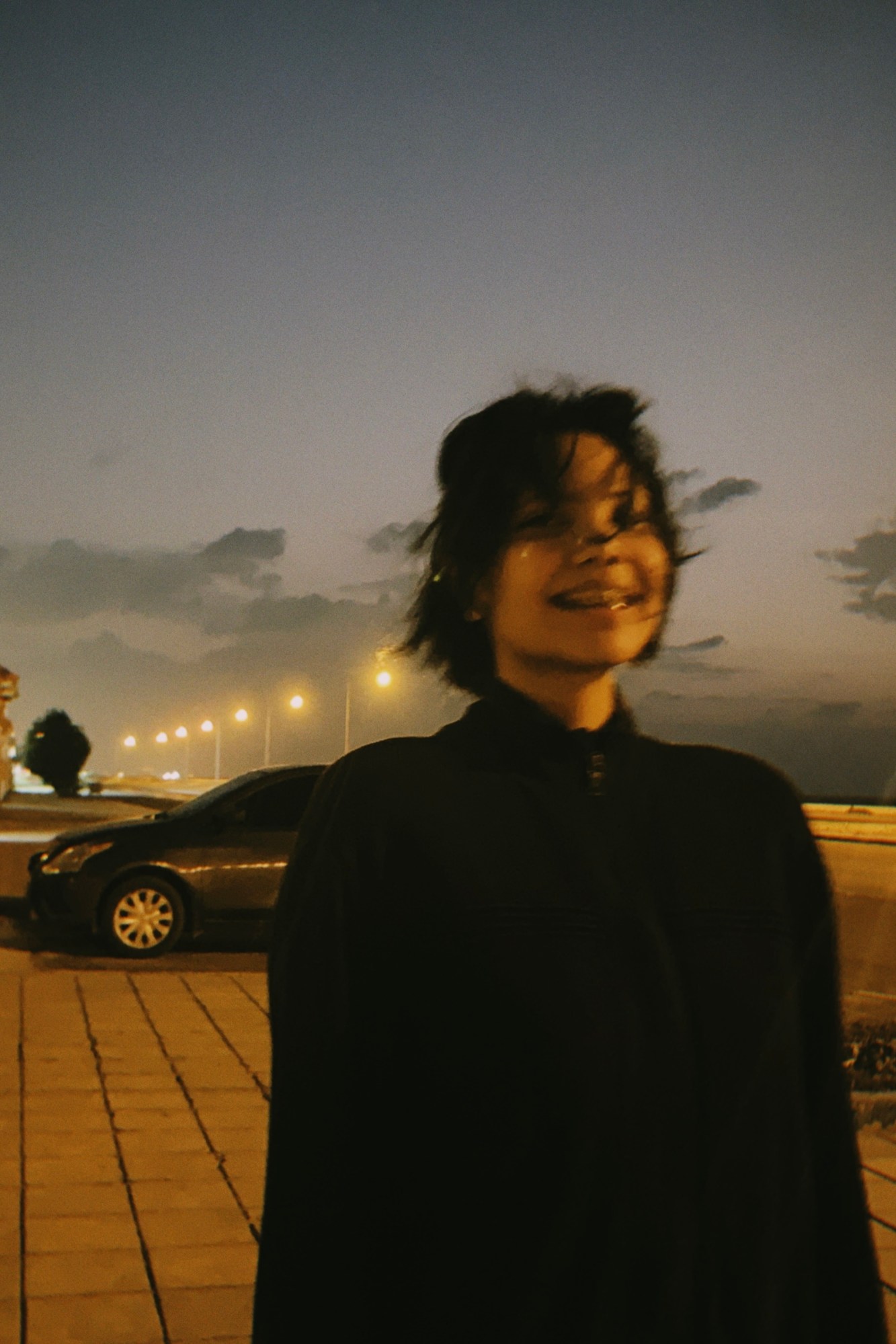 blurry image of a woman smiling in front of a parked car