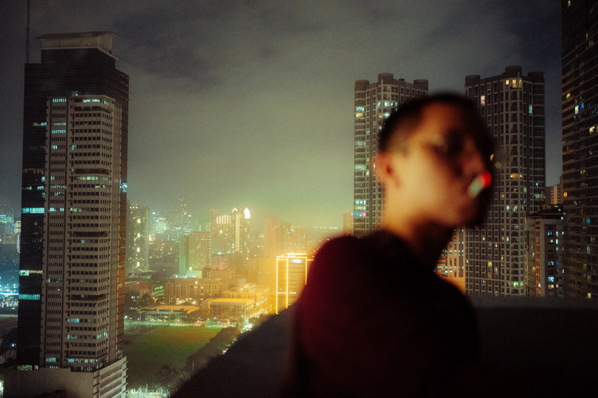 a blurry image of a man smoking in front of a cityscape at night