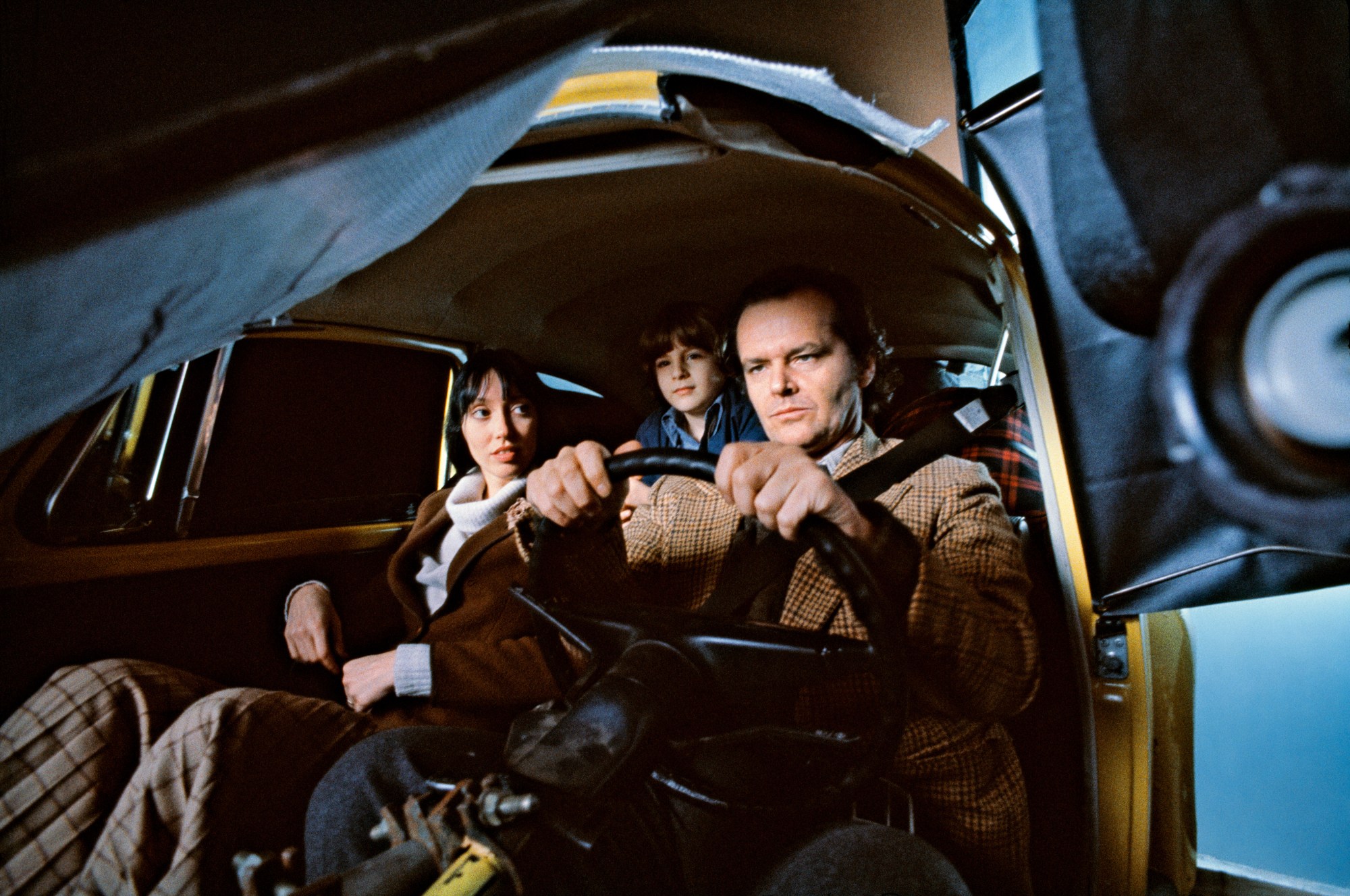 a behind the scenes photo of shelley duvall, jack nicholson and danny lloyd shooting the car scene in the shining