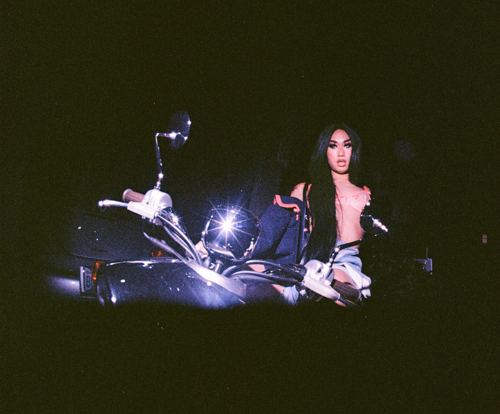 overexposed image of a drag queen sitting astride a motorcycle