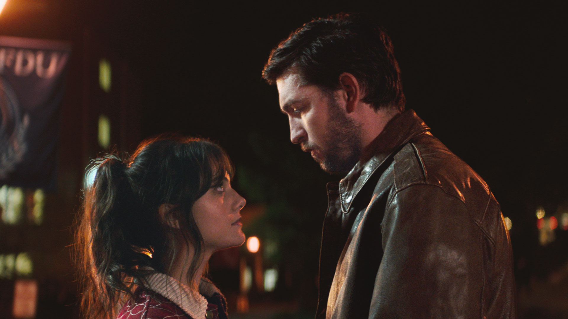 emilia jones and nicholas braun gaze at each other outside on a dark street