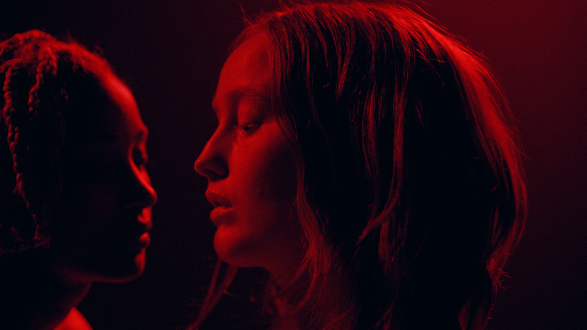 close up of two girls in a dark room lit with red light