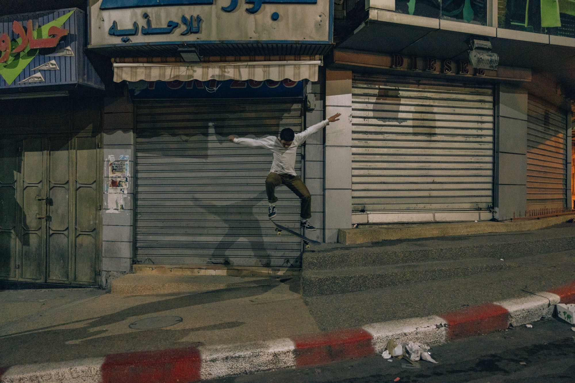 A young man skating on an empty street in Palestine.