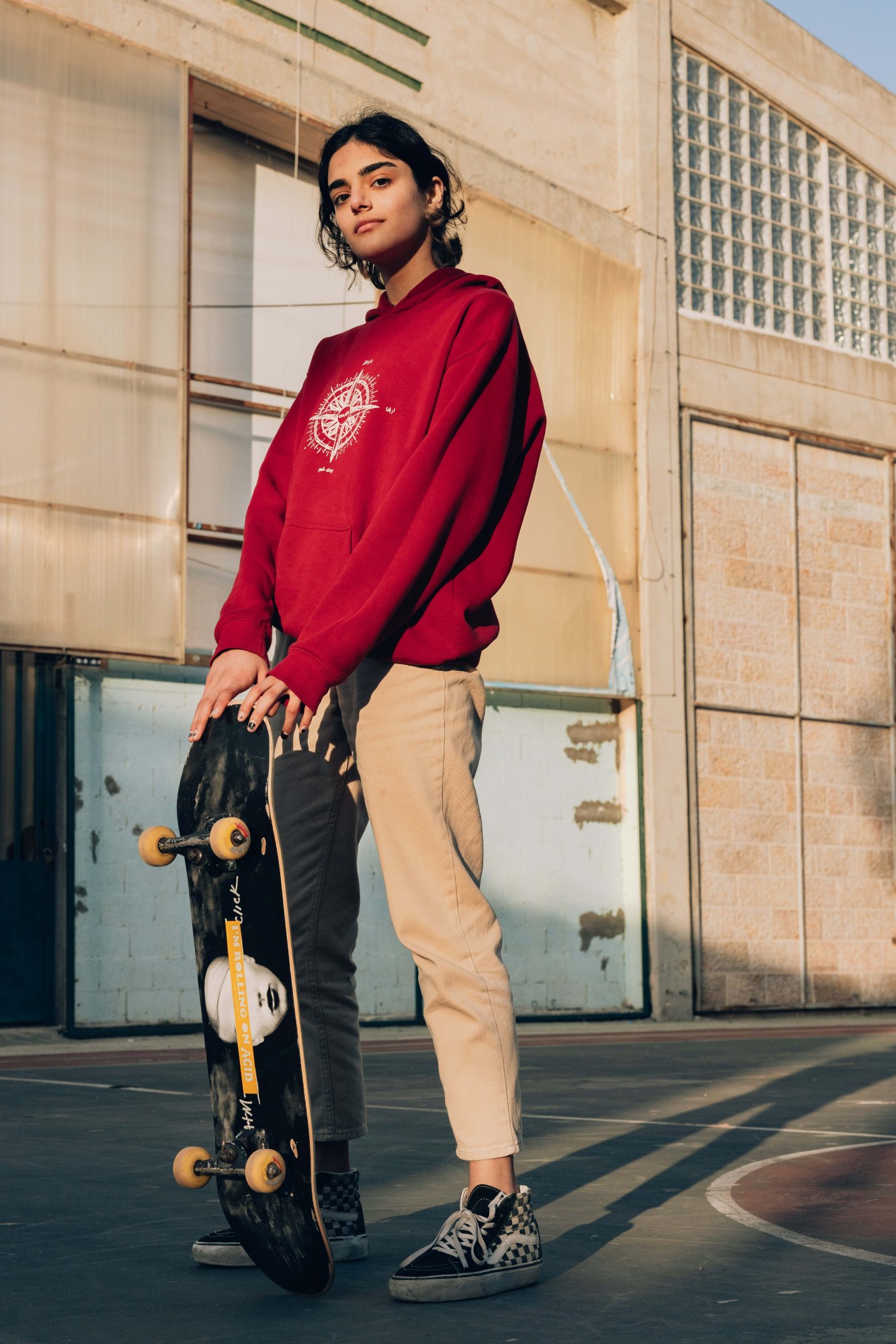 A young woman posing with her skateboard.